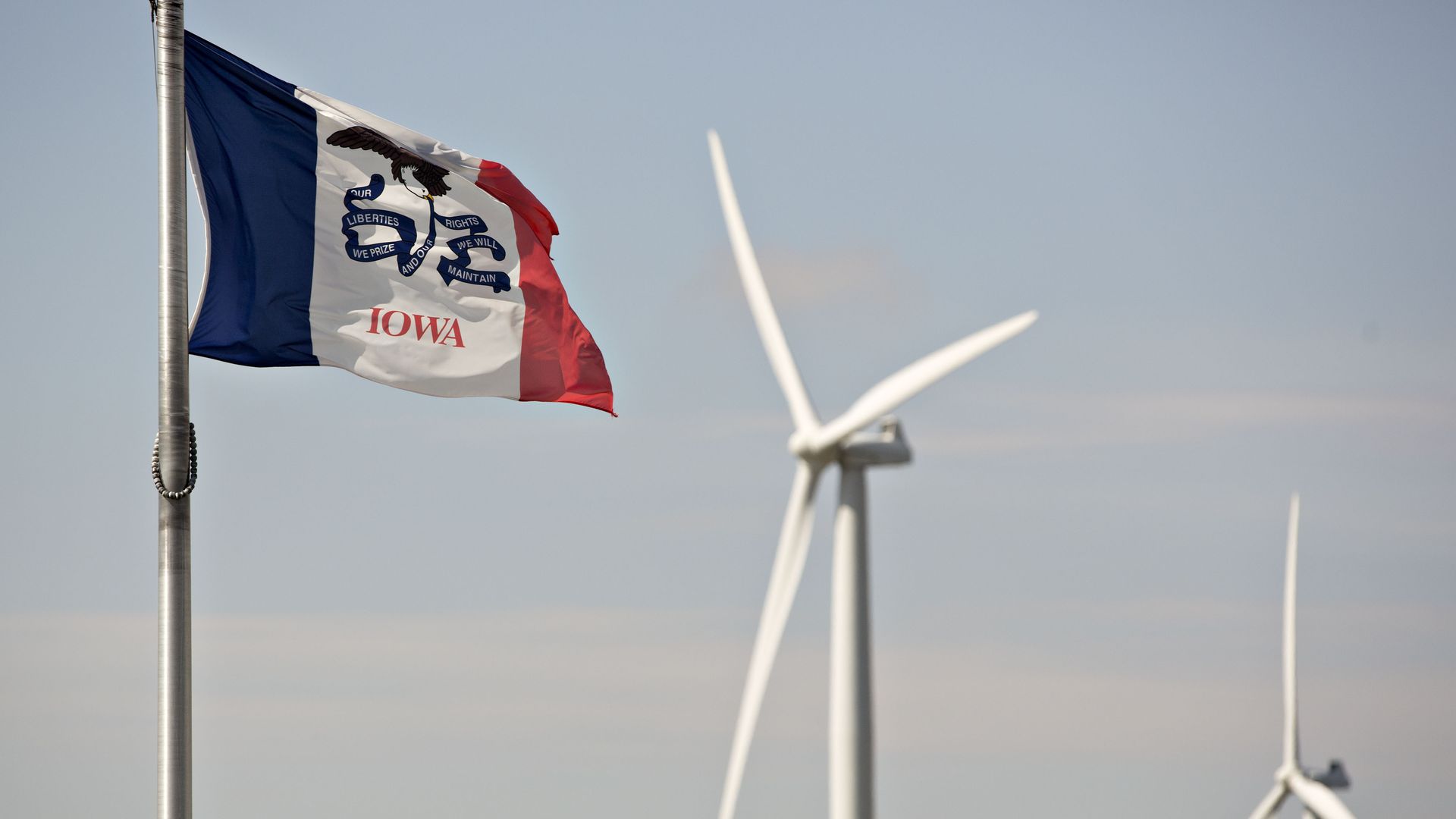 A photo of Iowa's state flag with a windmill in the background.