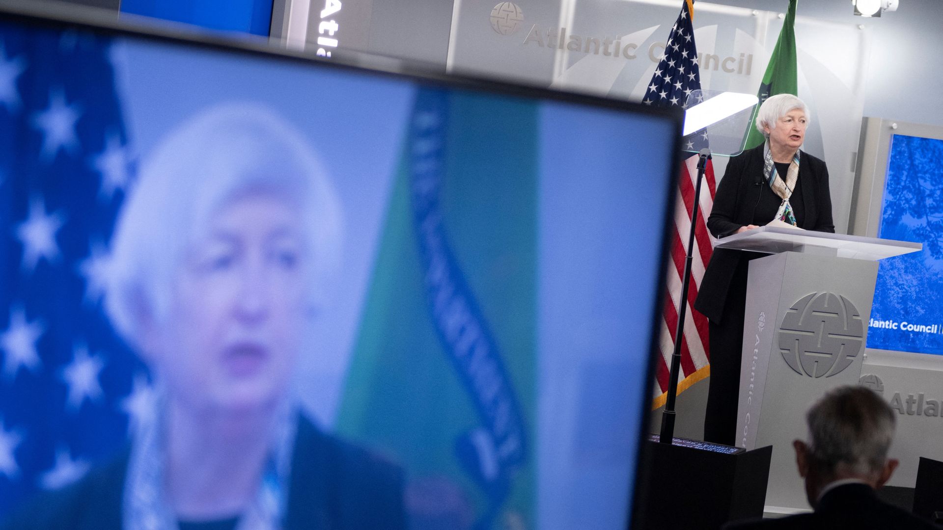 Treasury Secretary Janet Yellen is seen speaking news to a big-screen image of herself while addressing the Atlantic Council.