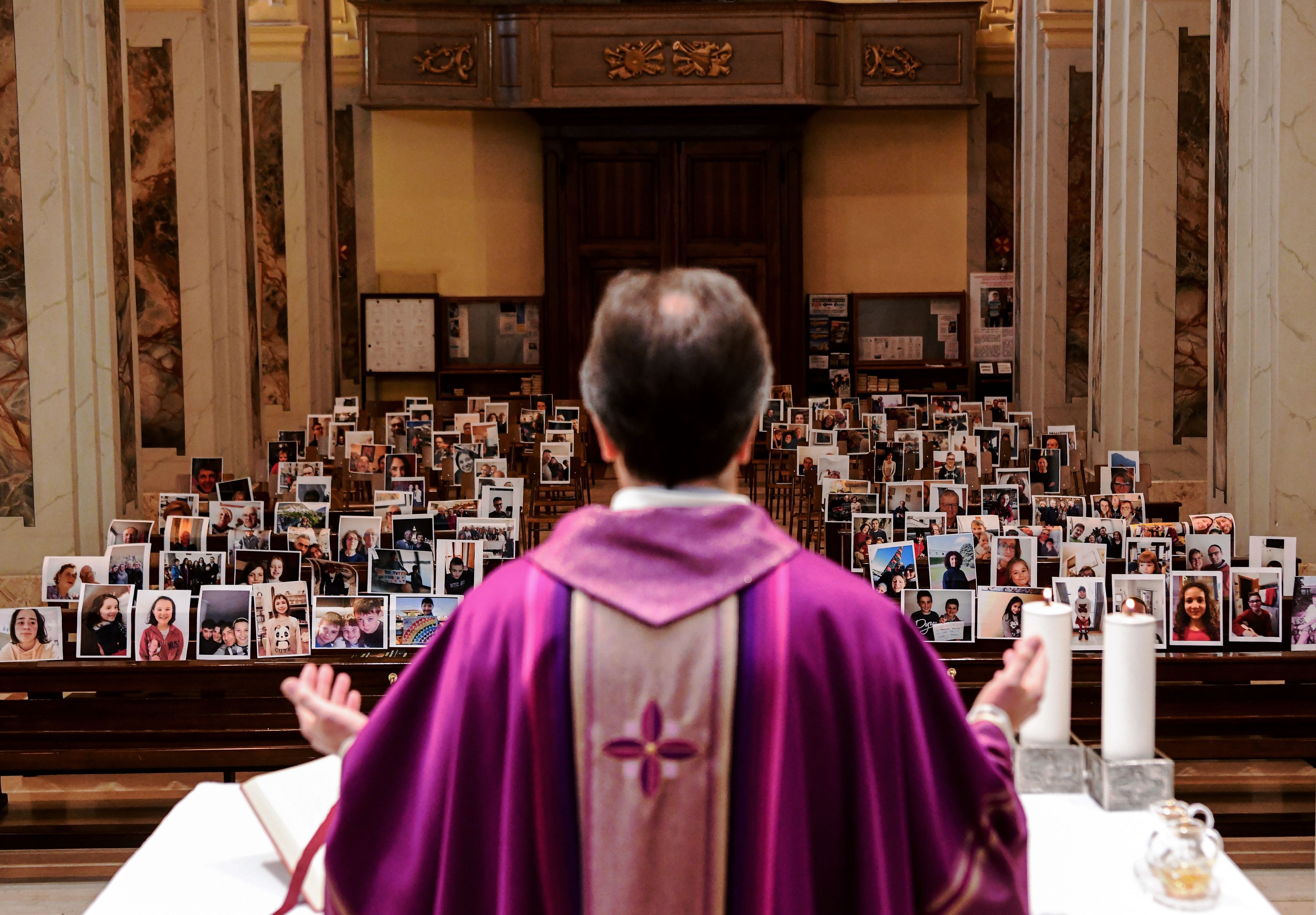Don Giuseppe Corbari, parson of the Church of Robbiano, holds Sunday mass as he looks towards selfie photographs sent in by his congregation members and glued to empty pews in Giussano 