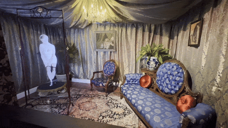 A hologram of a woman dressed like a prostitute appears in a mirror in a room designed like a 20th century brothel.