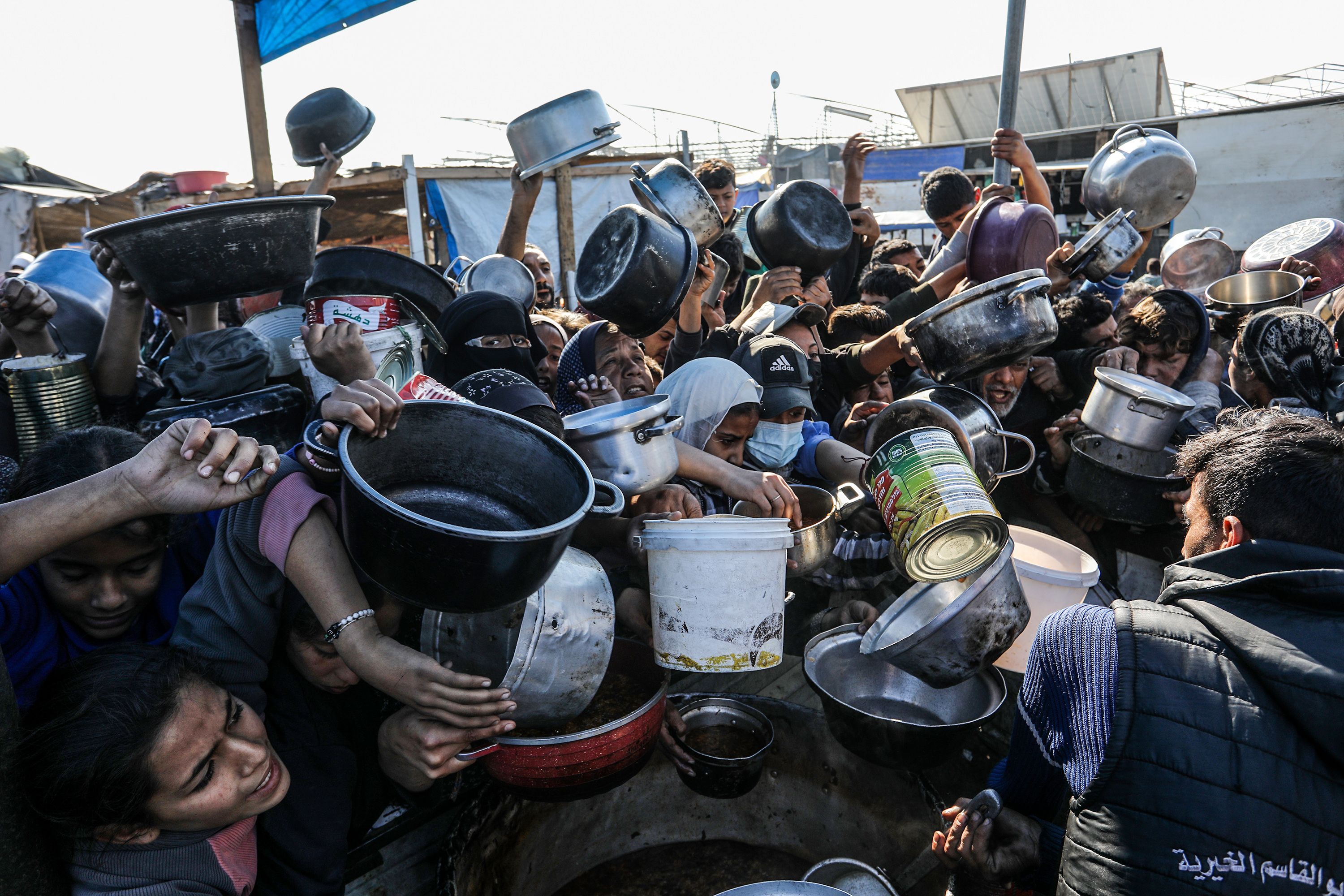 Palestinians, carrying empty pots, line up to receive meals, distributed by charity organizations, as people struggle with hunger due to embargo imposed by Israeli forces in Khan Yunis, Gaza on January 02, 2025. (Photo by Abed Rahim Khatib/Anadolu via Getty Images)