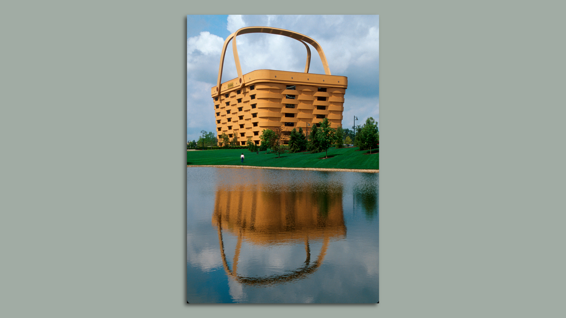 A large building in the shape of a basket, with a lake in the background.