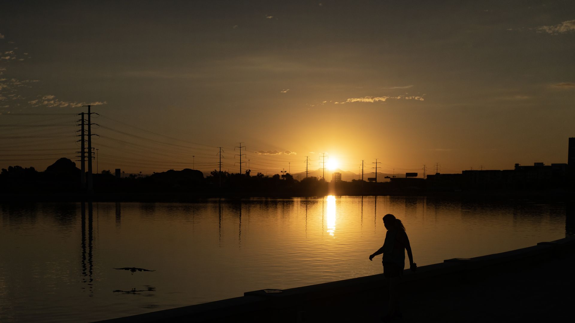 Picture of a woman walking with the sun low on the horizon during a heat wave in Arizona.
