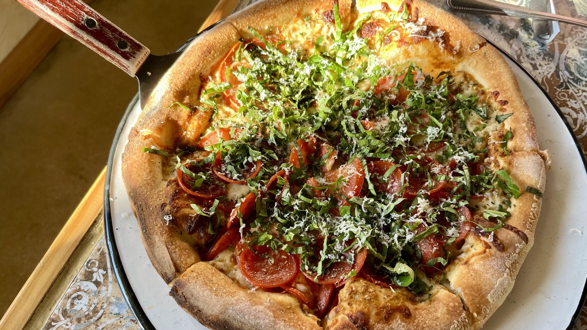 Light shines on a fresh pizza with pepperoni and margarita toppings.