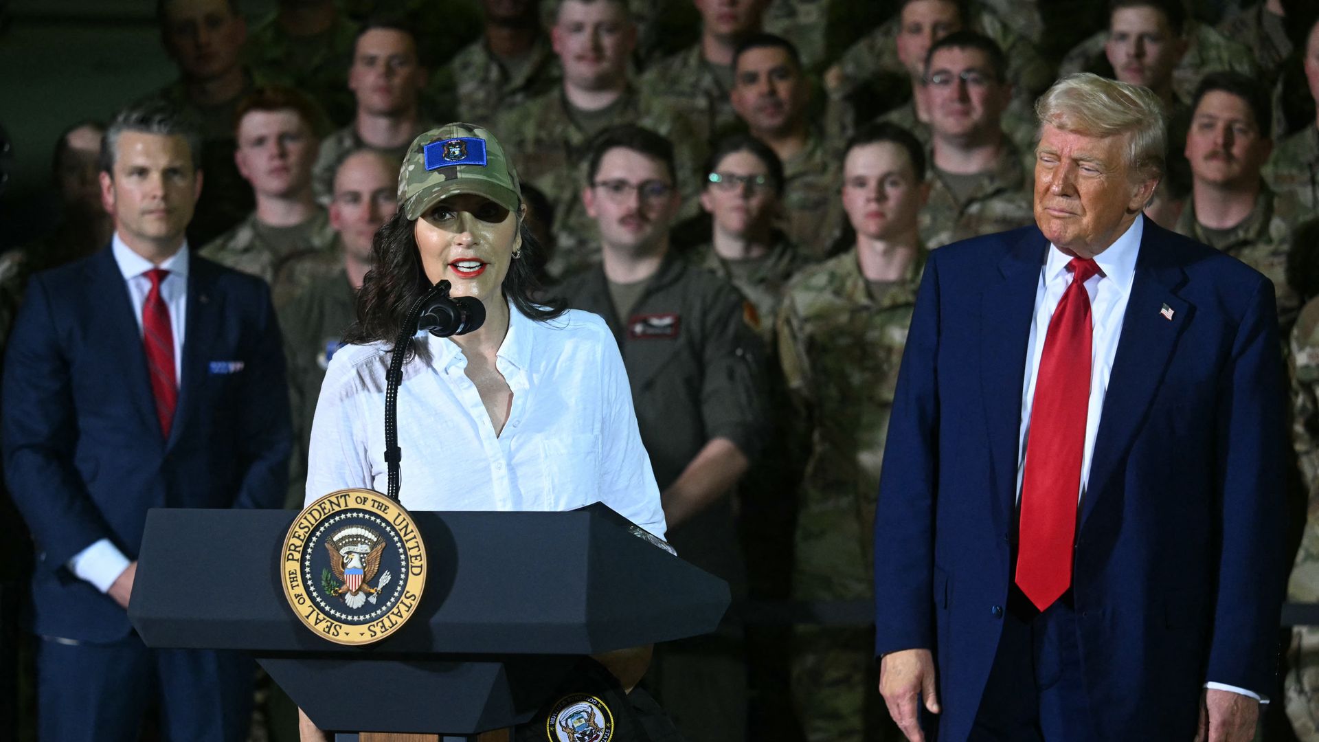 Michigan Gov. Gretchen Whitmer speaks behind a podium with President Trump to her left.