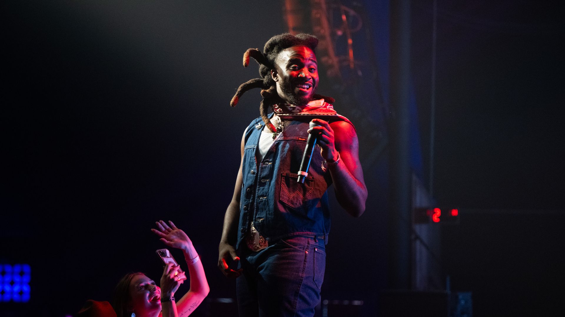 Singer Shaboozey onstage smiling and holding a mic.