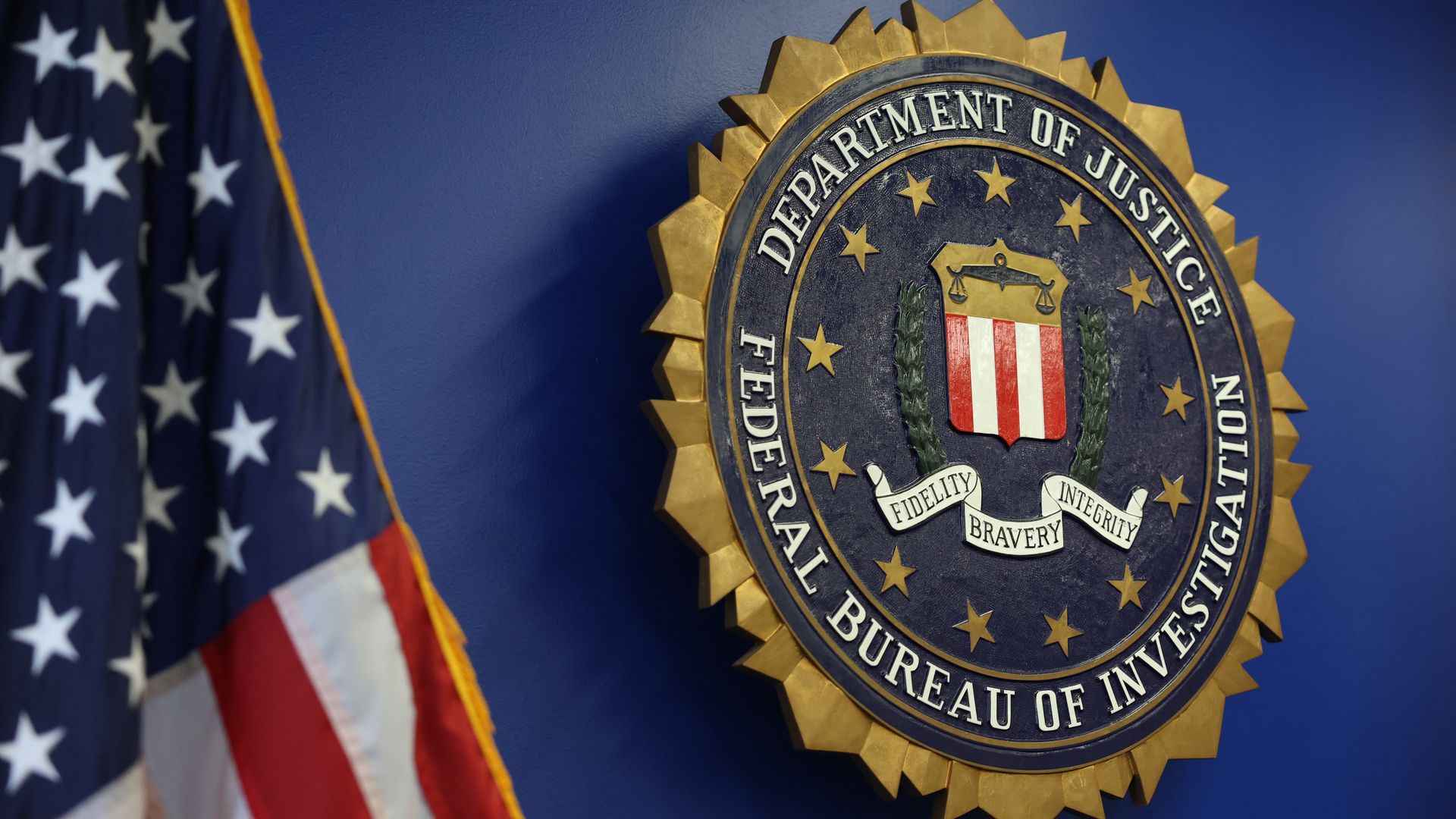 FBI crest on blue background with US flag on side.