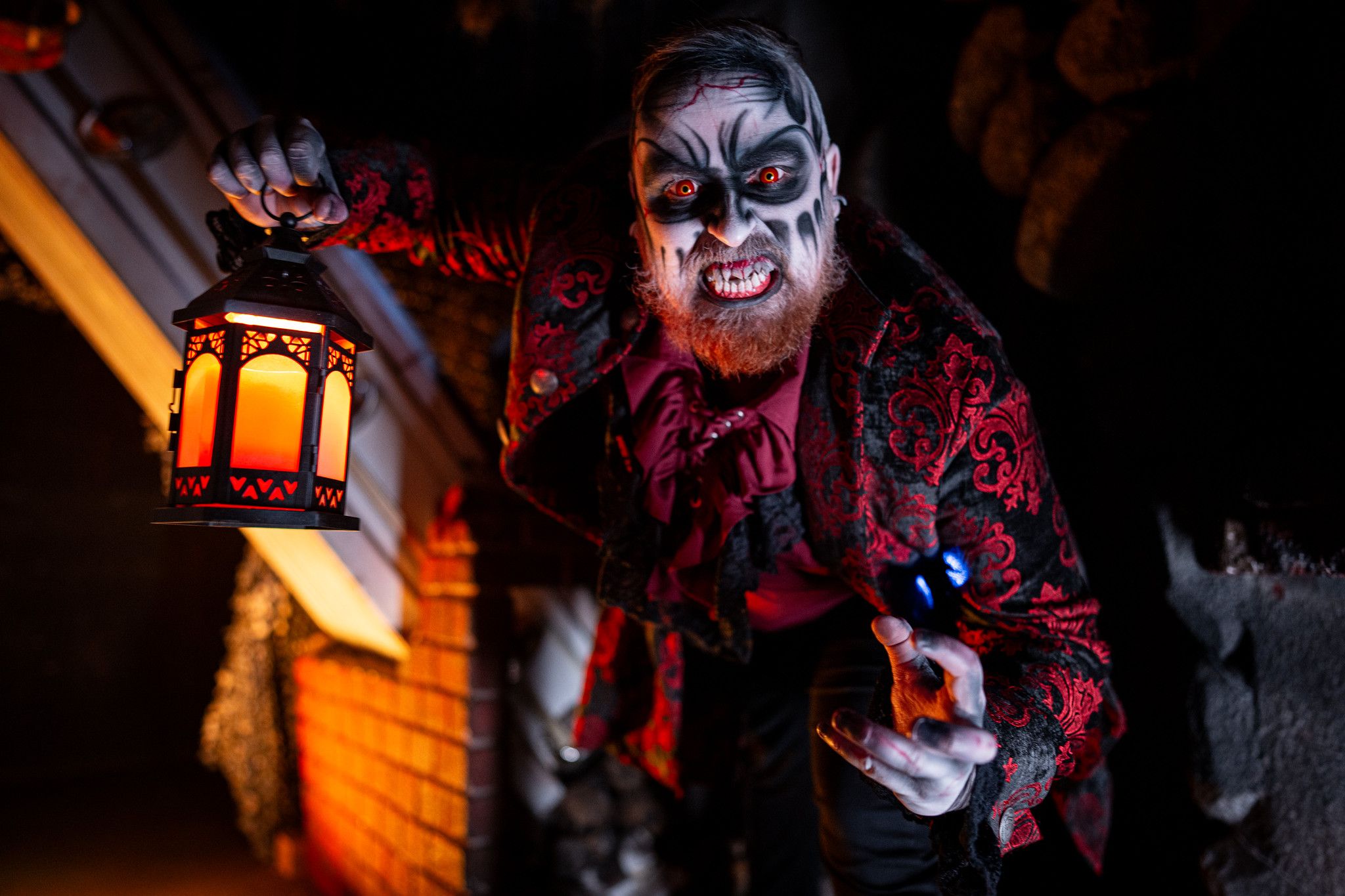 A person dressed up as a scary ghoul with face paint and a red suit snarls at the camera