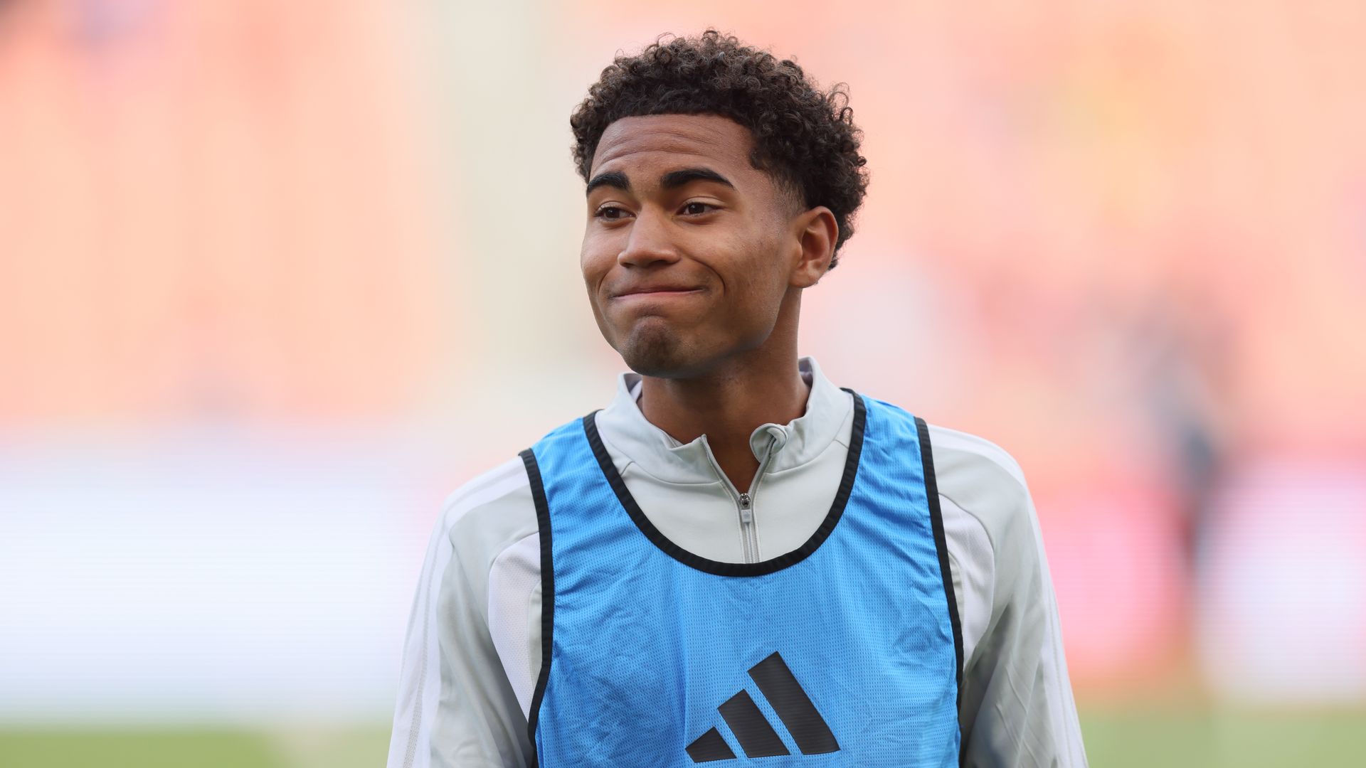 A soccer player wears a white shirt and blue bib