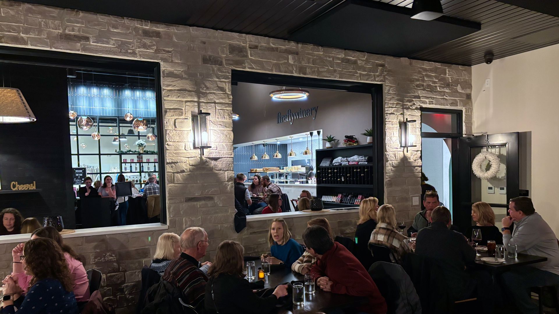 An overview of Firefly Winery, with crowds at tables and two windows in a wall that show another gathering area 