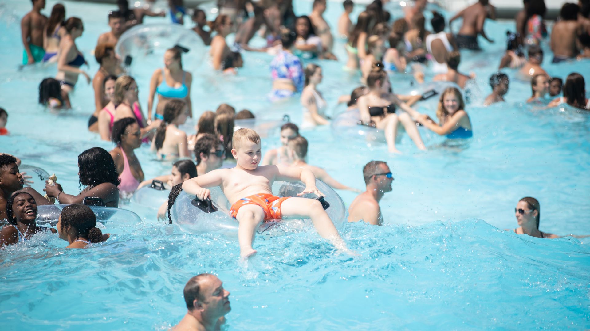 Boy sitting in a tube among a large crowd of swimmers at the Settlers Cabin Wave Pool in Robinson, Pa.