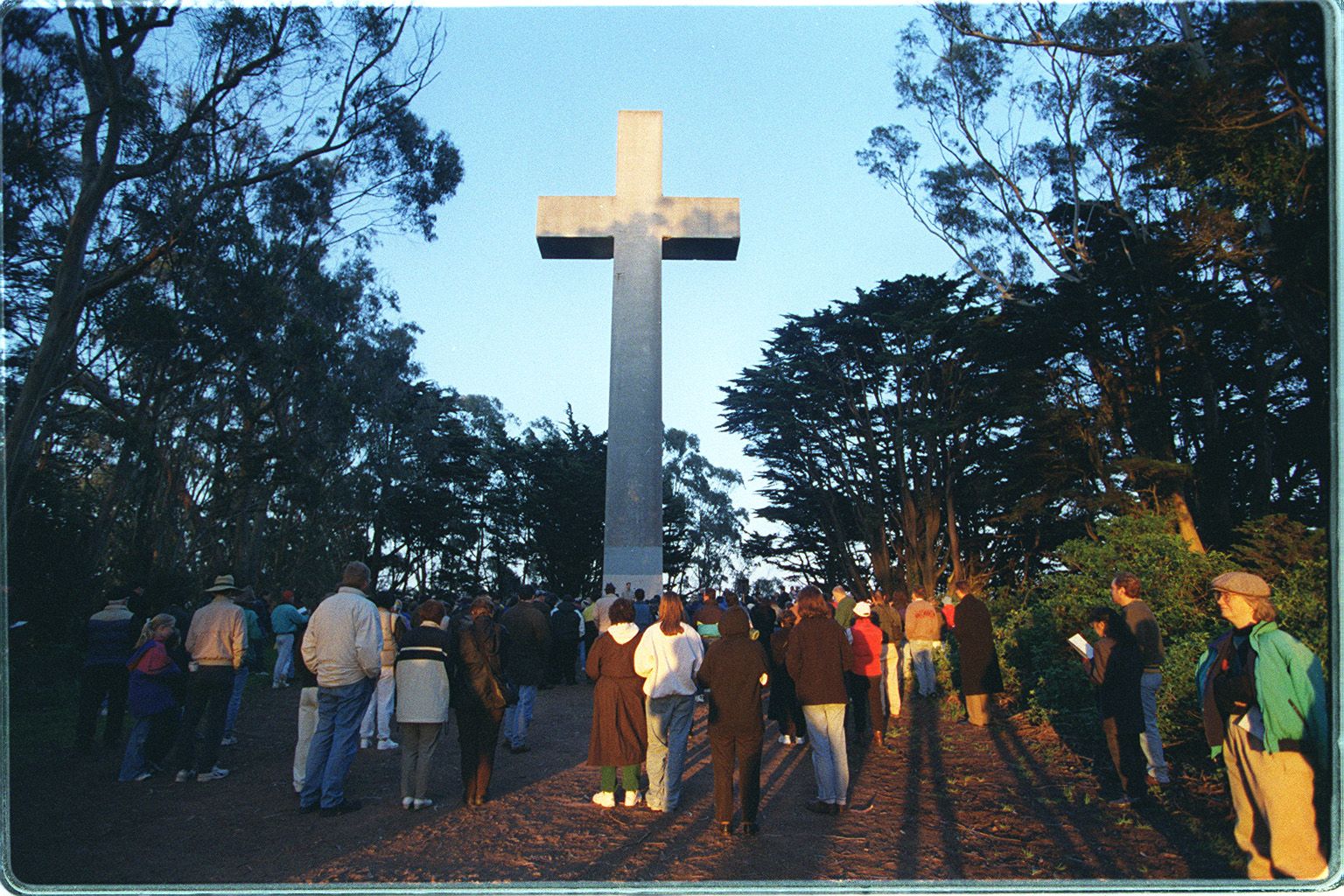 group of people at the easter sunrise service in front of giant cross among trees