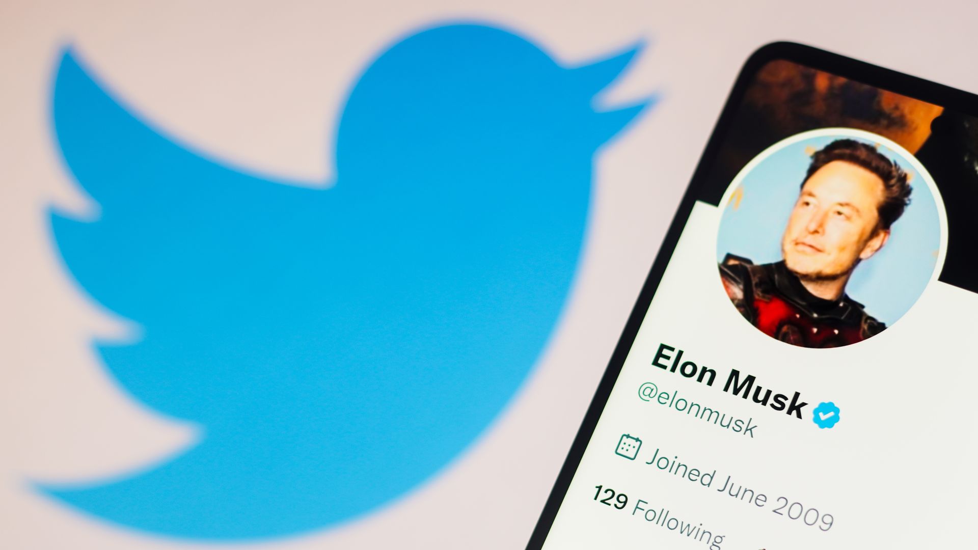 photo illustration, the Elon Musk Twitter account seen displayed on a smartphone and Twitter logo in the background. 