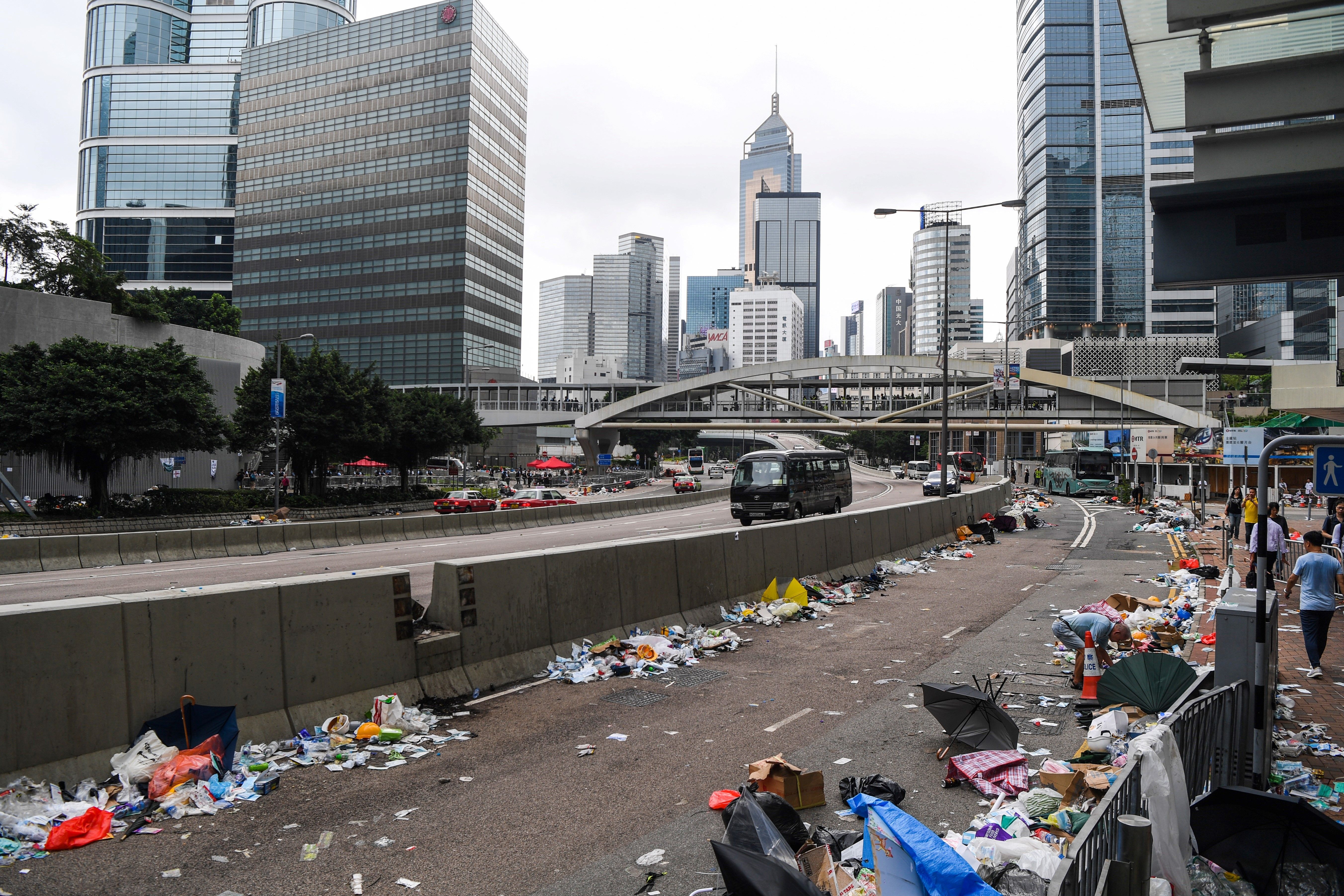 People walk on a street full of debris a day after a demonstration against a controversial extradition law proposal in Hong Kong on June 13, 2019.