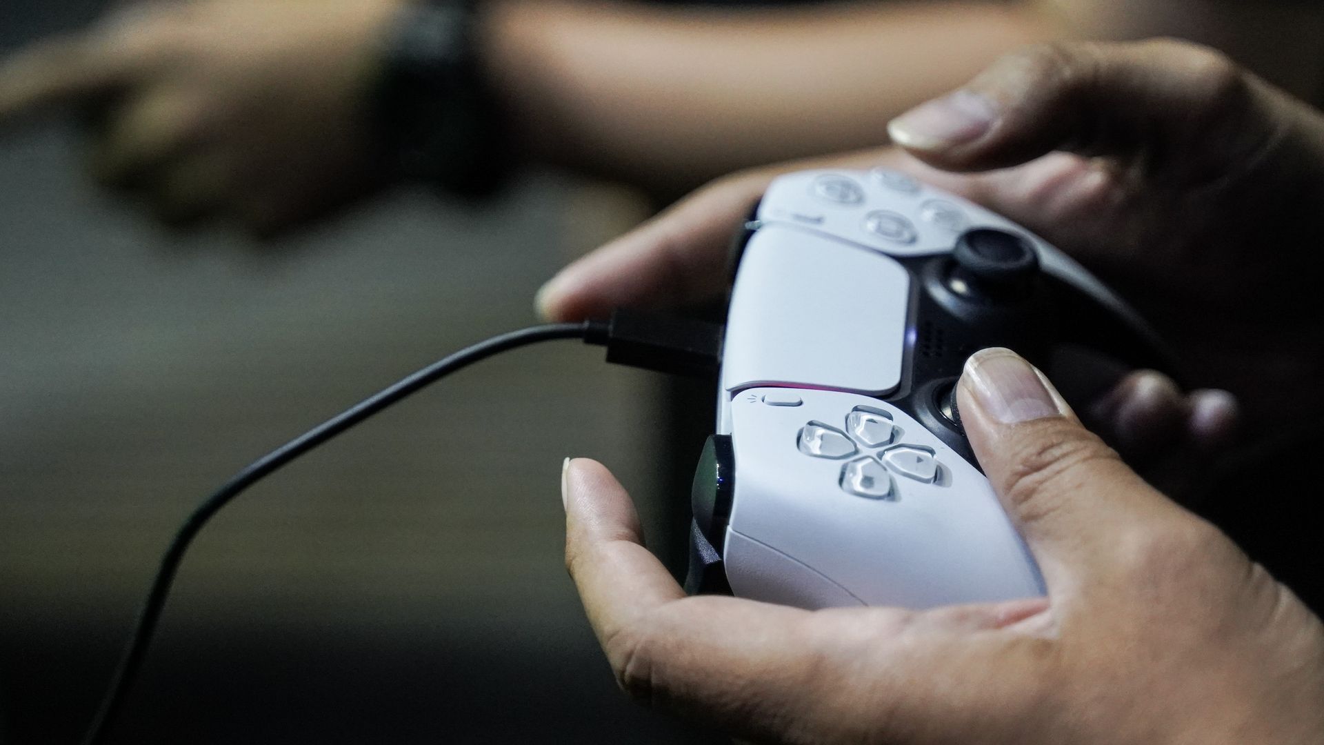 A close-up shot of a person's hands, which are holding a Playstation 5 controller.