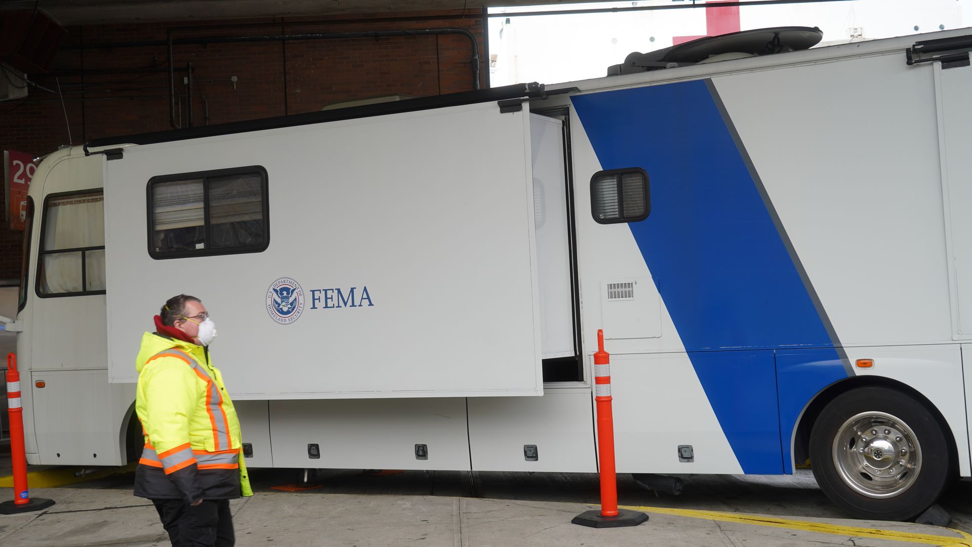 A white FEMA van with a masked worker nearby.
