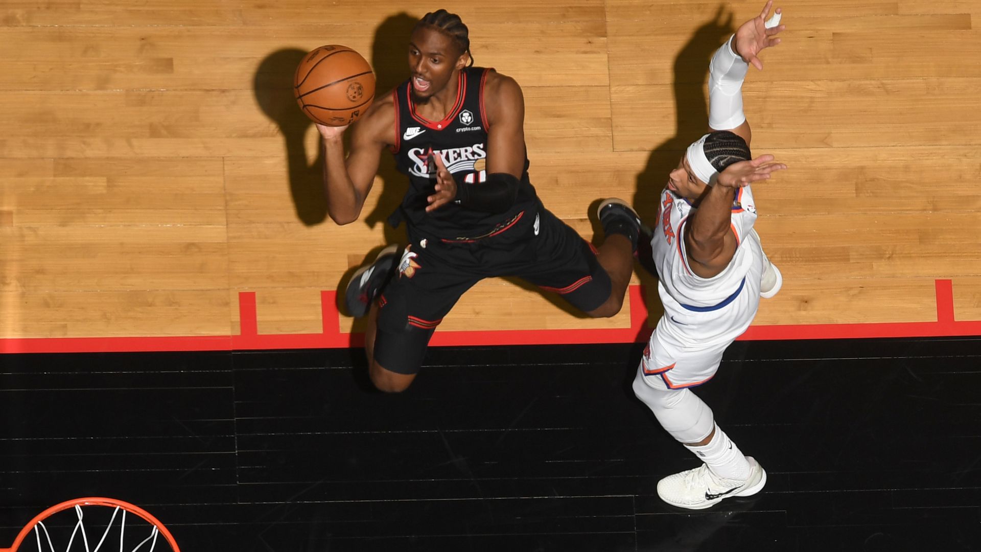 A above-the-rim view of Sixers guard Tyrese Maxey putting up a leaning shot over a Knicks defender.