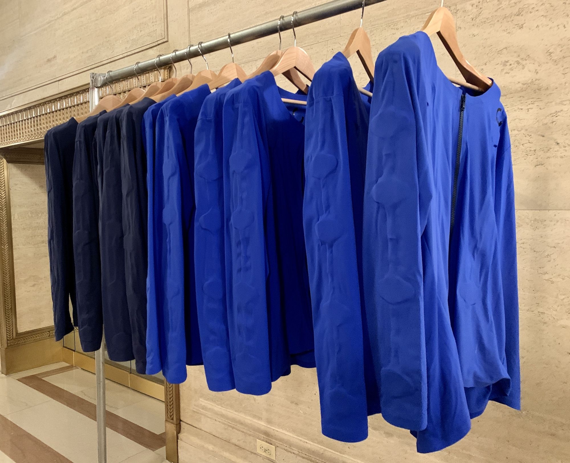 Dark blue and bright blue shirts on hangers on a clothing rack.