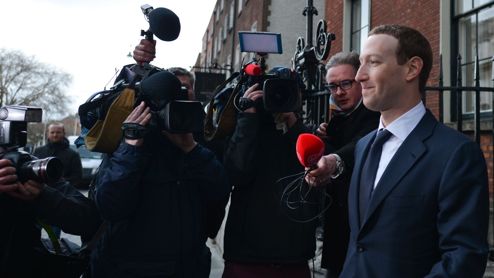 A man walks by reporters and TV cameras