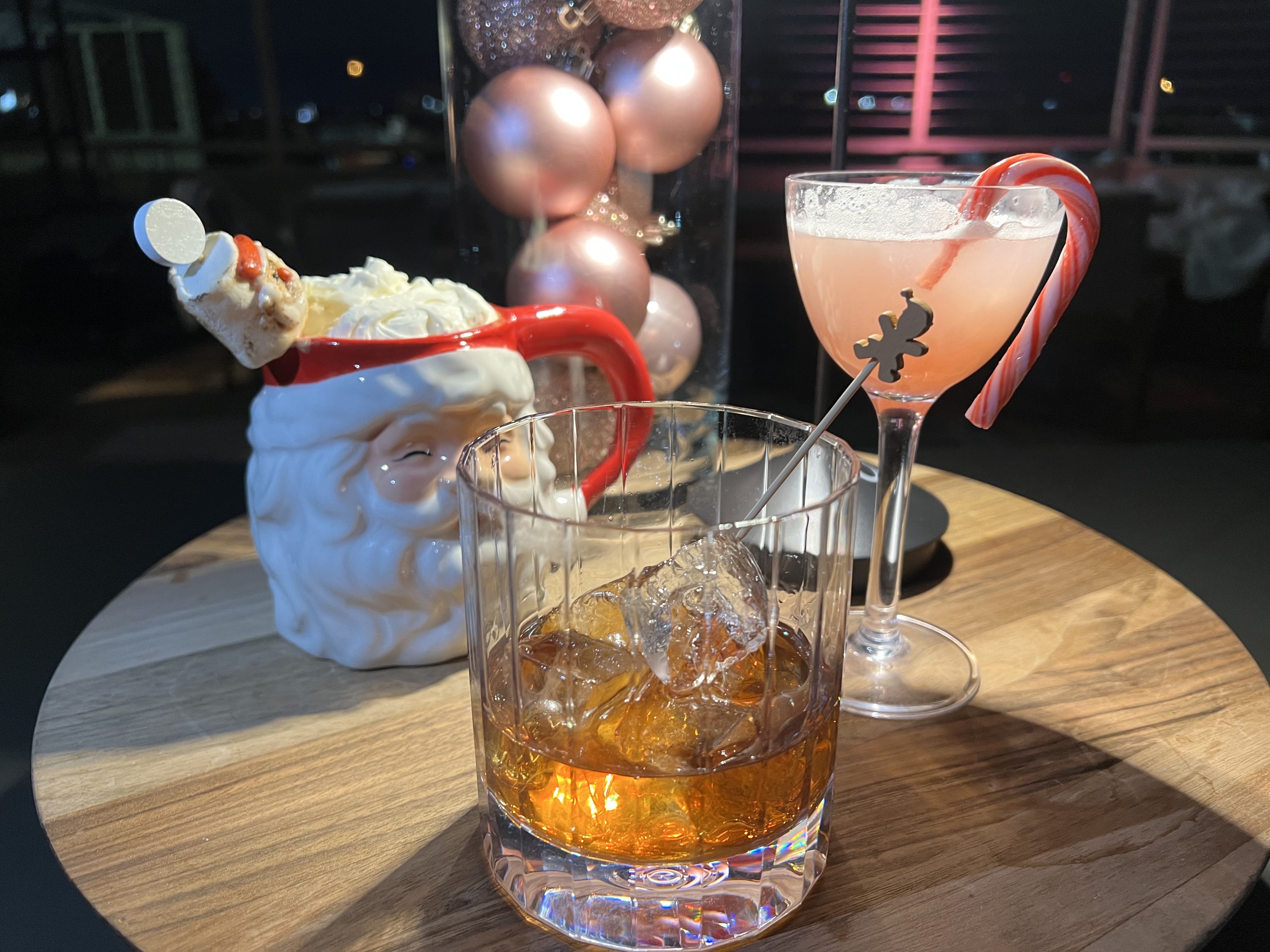Three holiday-themed cocktails arranged on a small wooden table. 