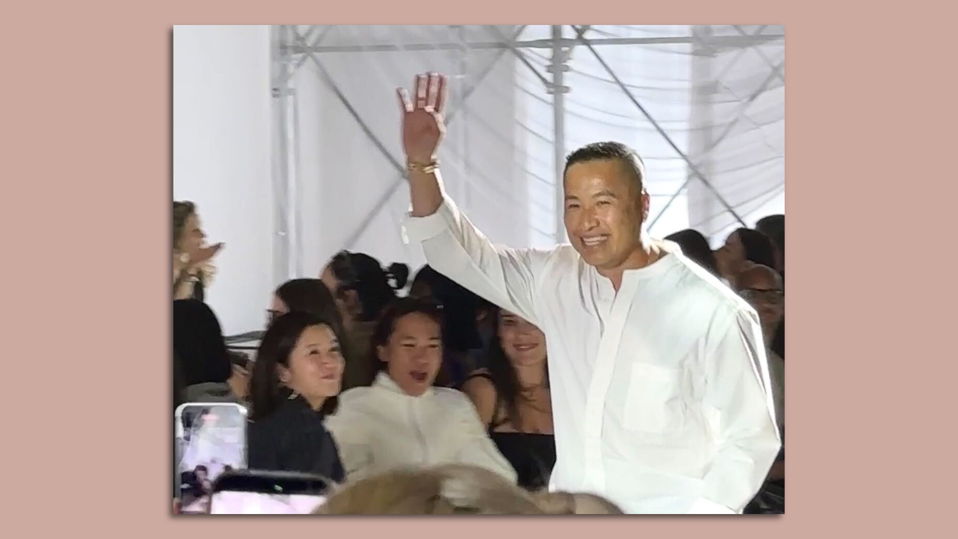photo of a man wearing a white shirt waving to a crowd at New York Fashion Week