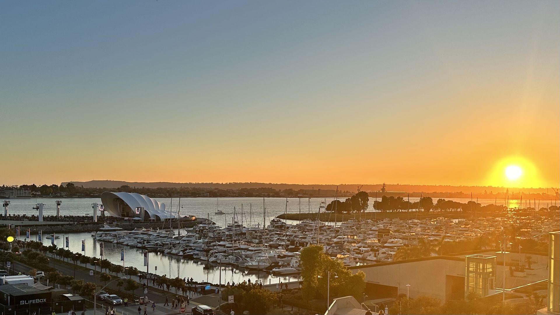 A concert venue in a harbor with the sun setting behind it