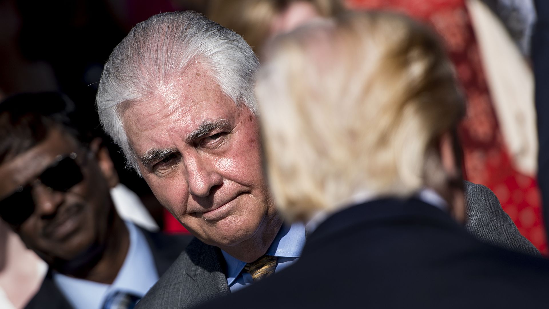 In this image, Tillerson looks at Trump. Only the back of Trump's head faces the camera. 