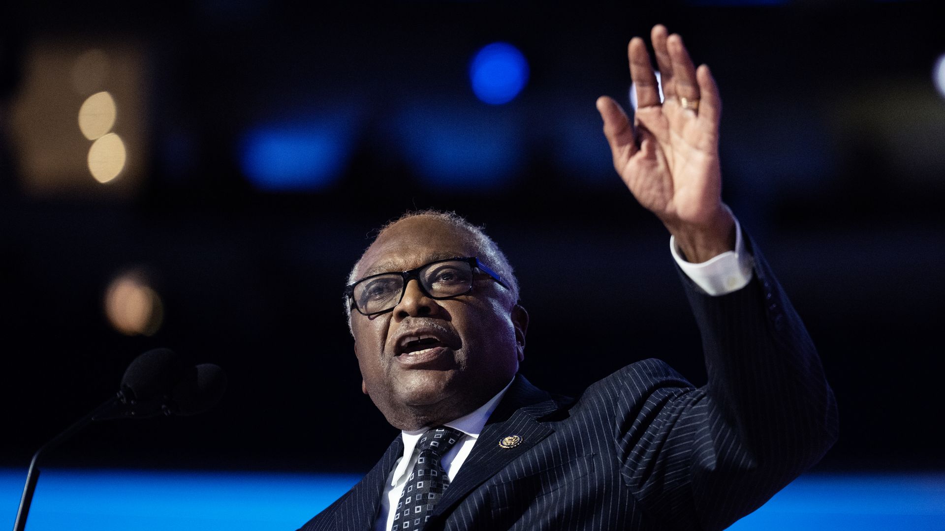 Rep. Jim Clyburn, wearing a pinstripe suit and speaking at a podium with his hand raised.