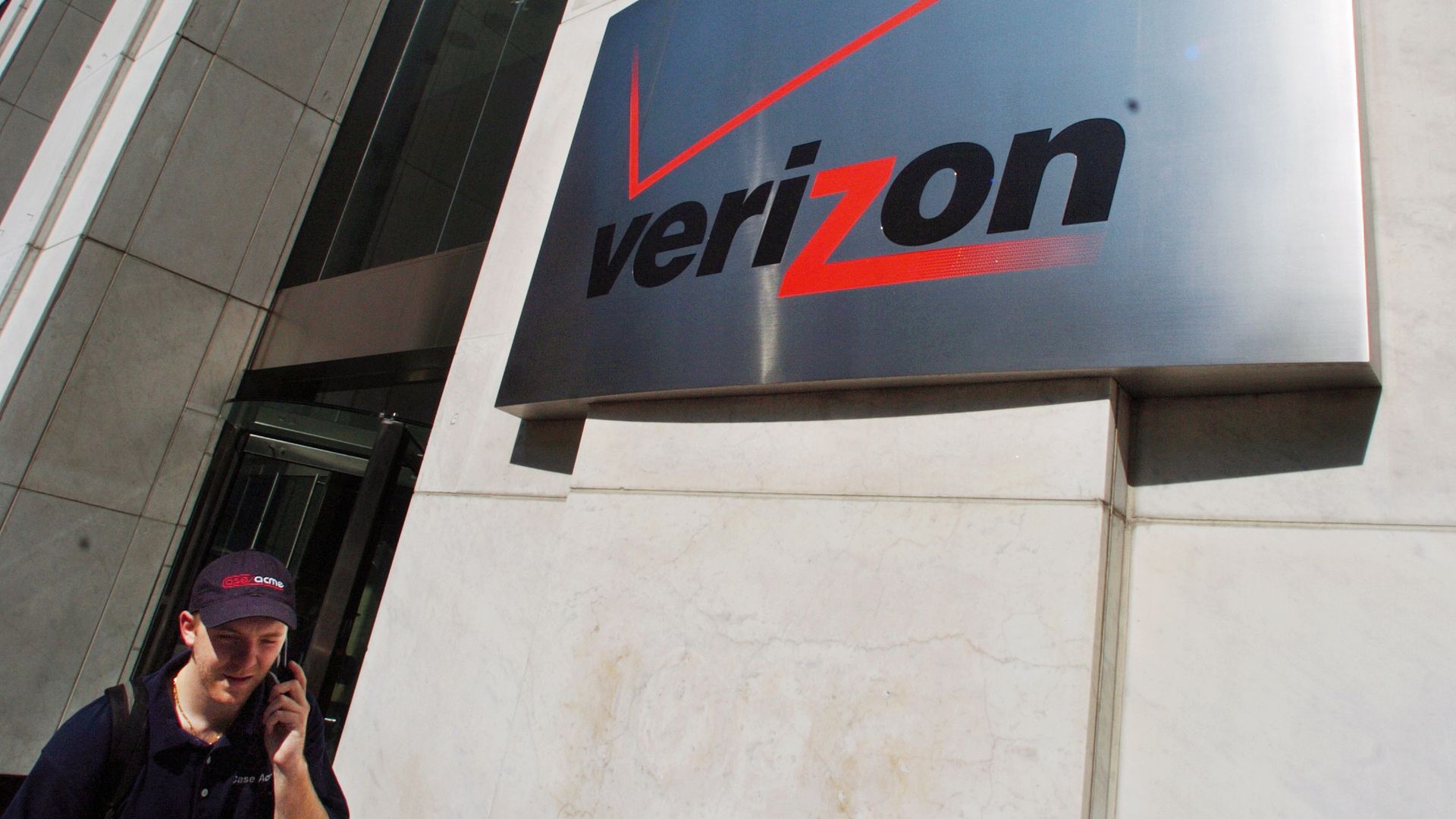 A pedestrian talks on his cell phone while walking past the Verizon Communications Inc. headquarters in New York on Tuesday, July 26, 2005.