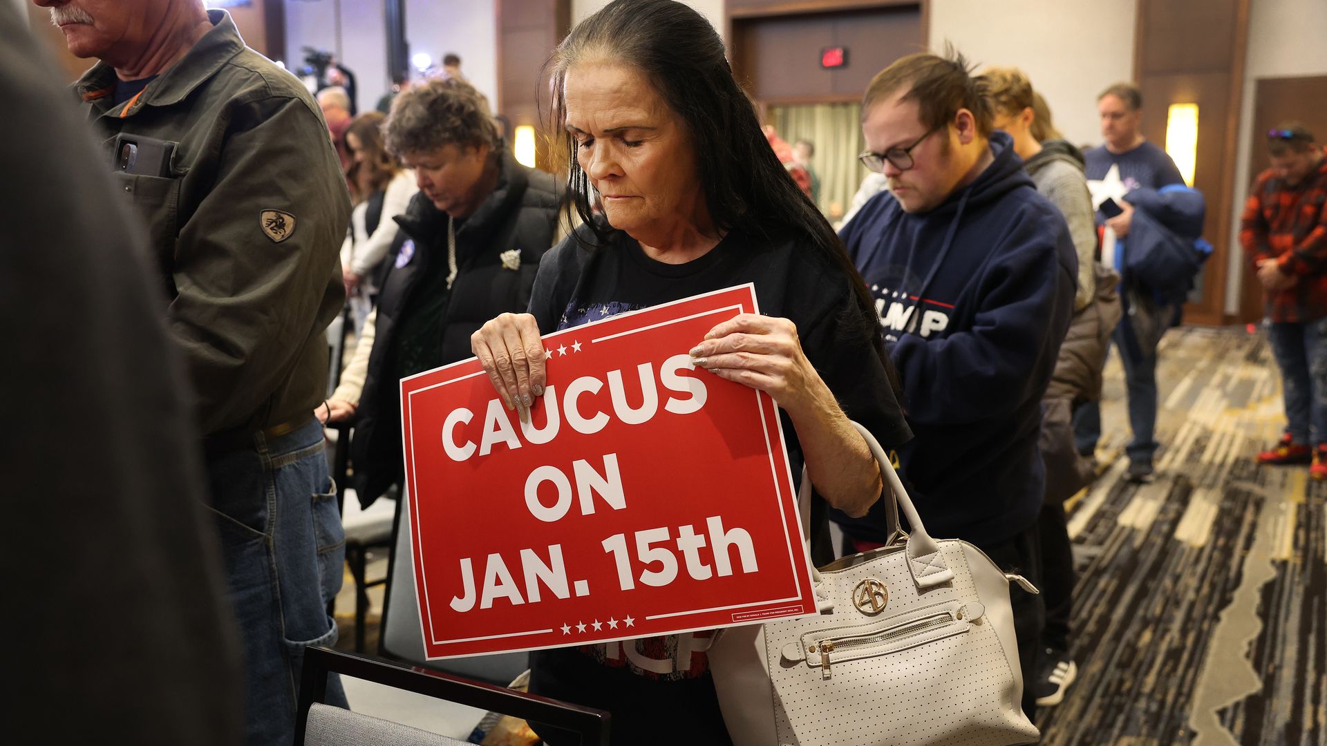 A photo of a woman holding an Iowa caucus sign.