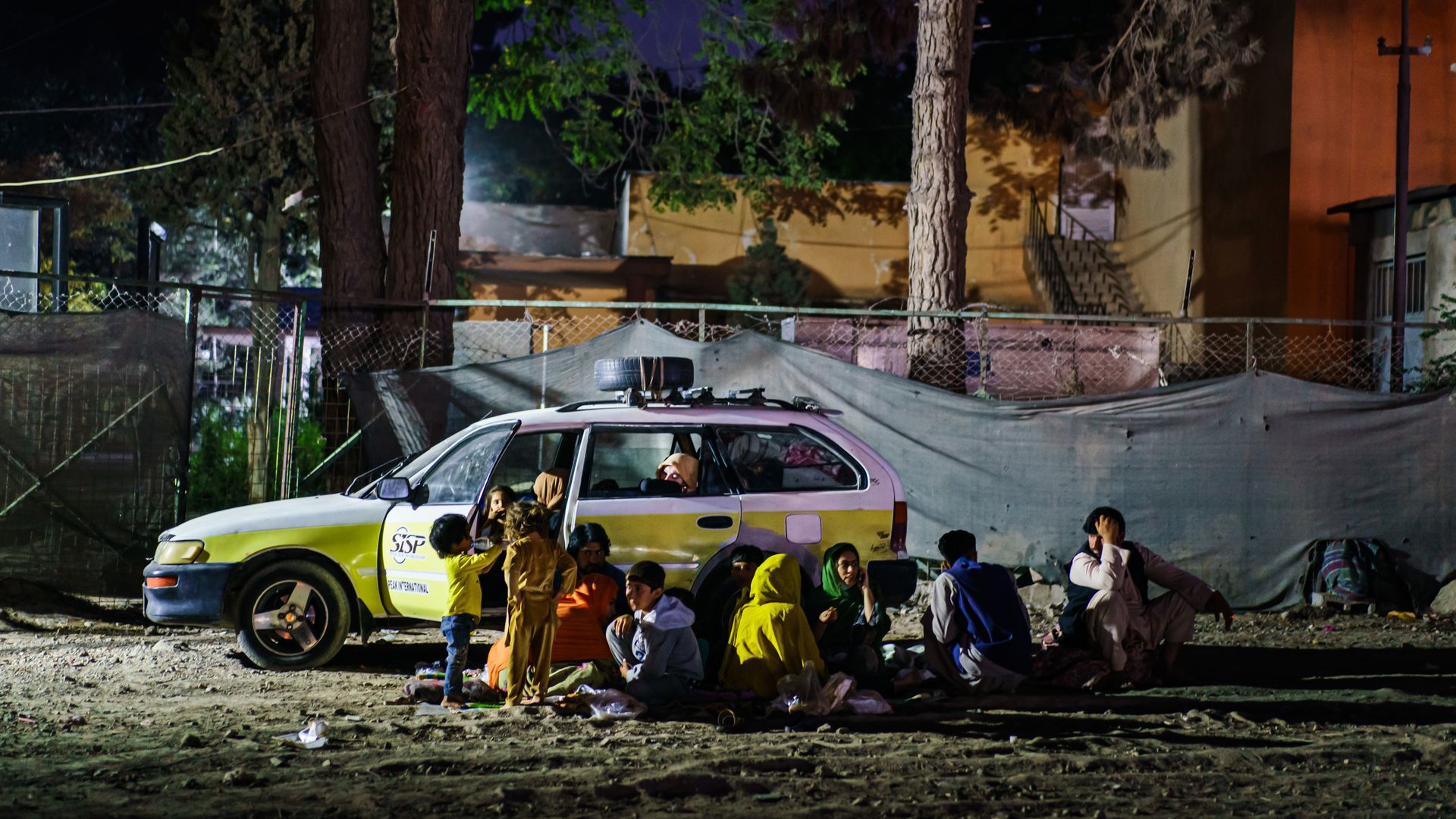 A small group of Afghans camp out in the corner of a parking area
