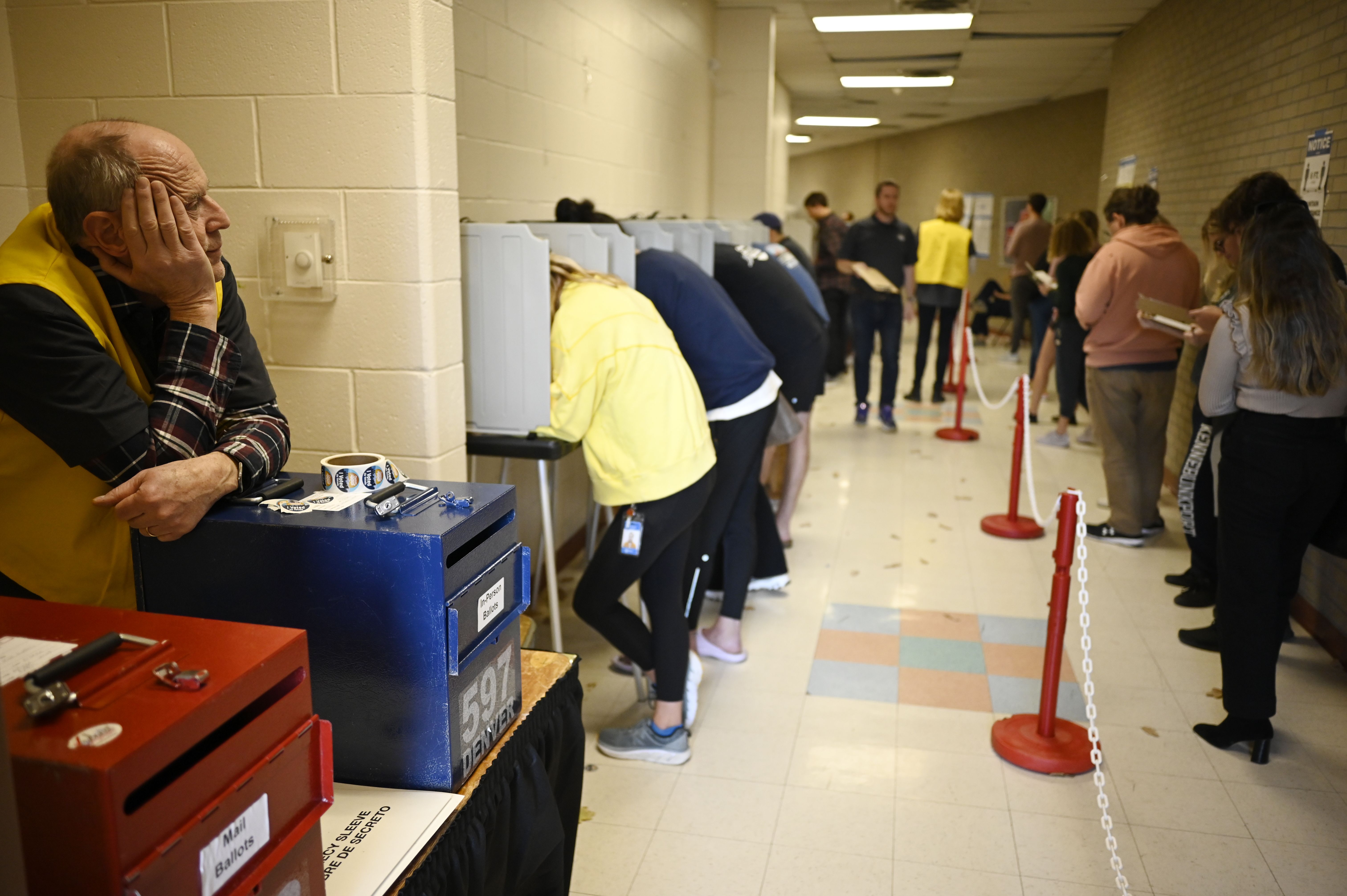 Election Judge John Franco, left, is watching voters waiting in the line at Voter Service and Polling Center in North High school in Denver, Colorado.