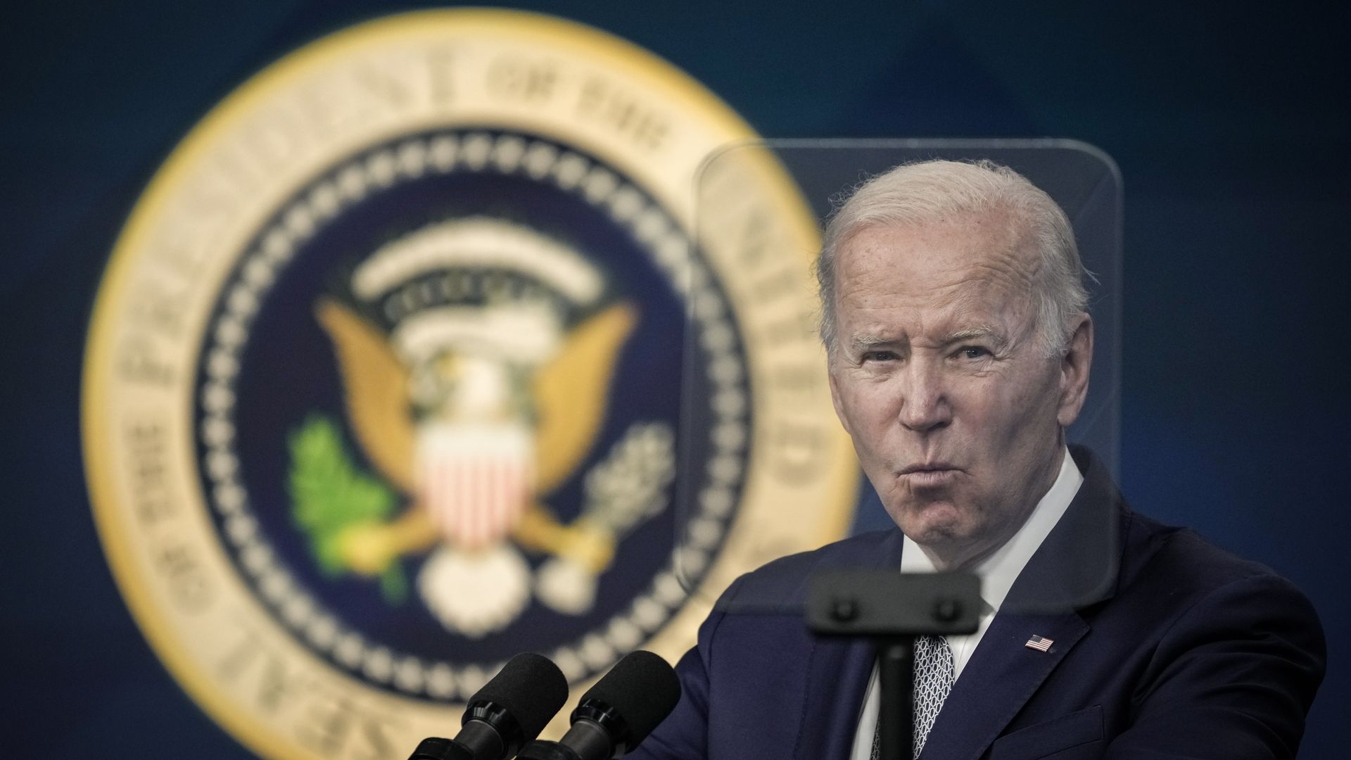 President Biden is seen through the pane of a TelePrompTer as he speaks Tuesday.
