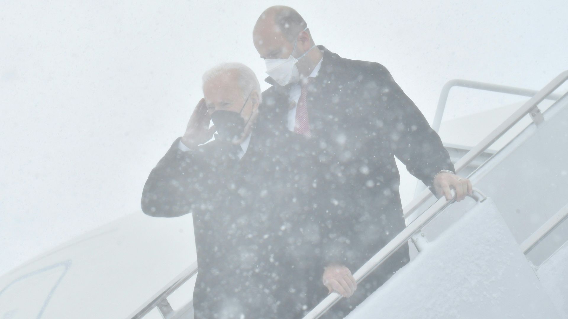 A Secret Service agent is seen shadowing President Biden as he descends snow-covered steps from Air Force One.