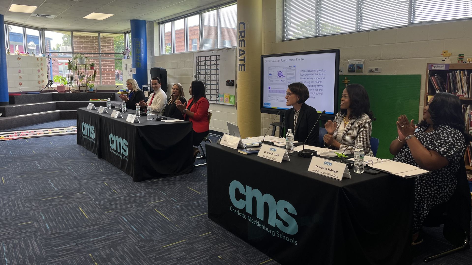 CMS senior leadership and principals sit at tables in media center