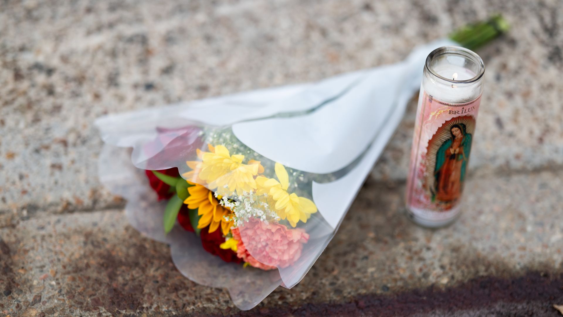 Photo of a bouquet of flowers and a devotion candle on the streets.