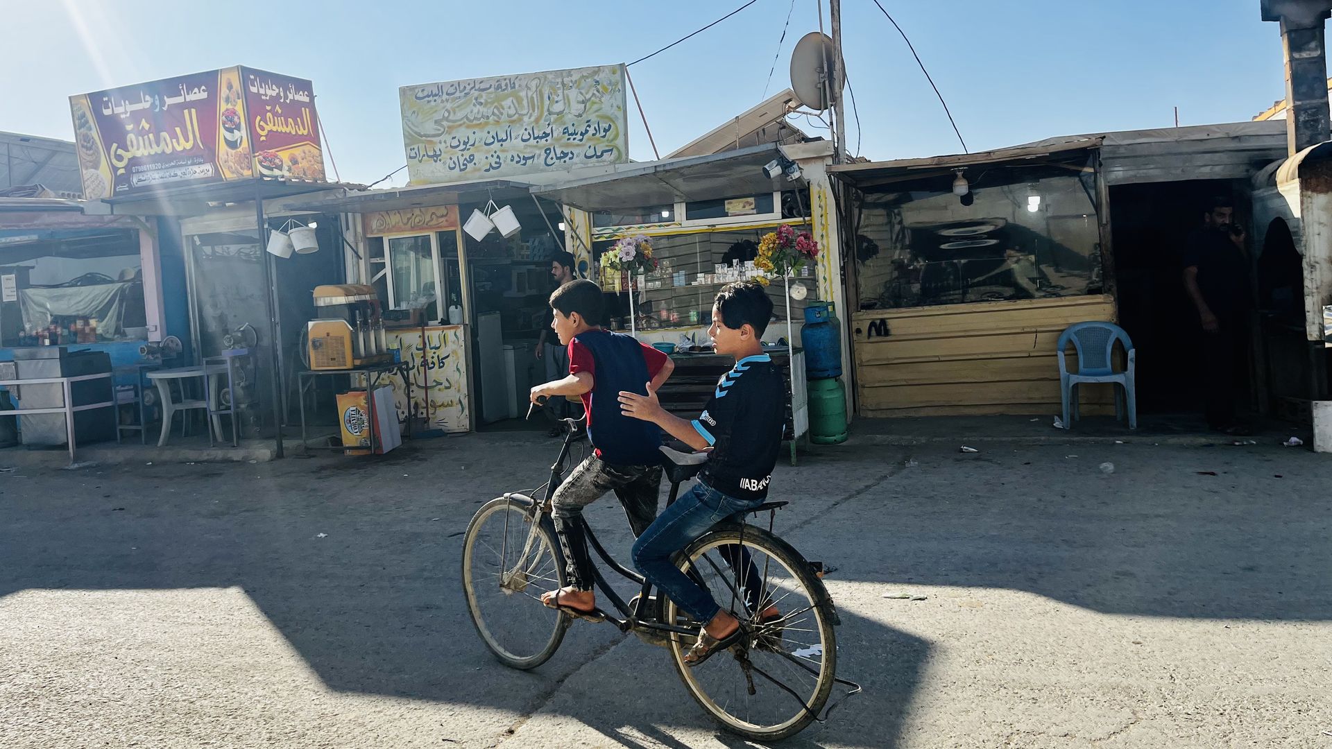 Two Syrian refugee boys ride bikes down a street in Zaatari Refugee Camp in Jordan