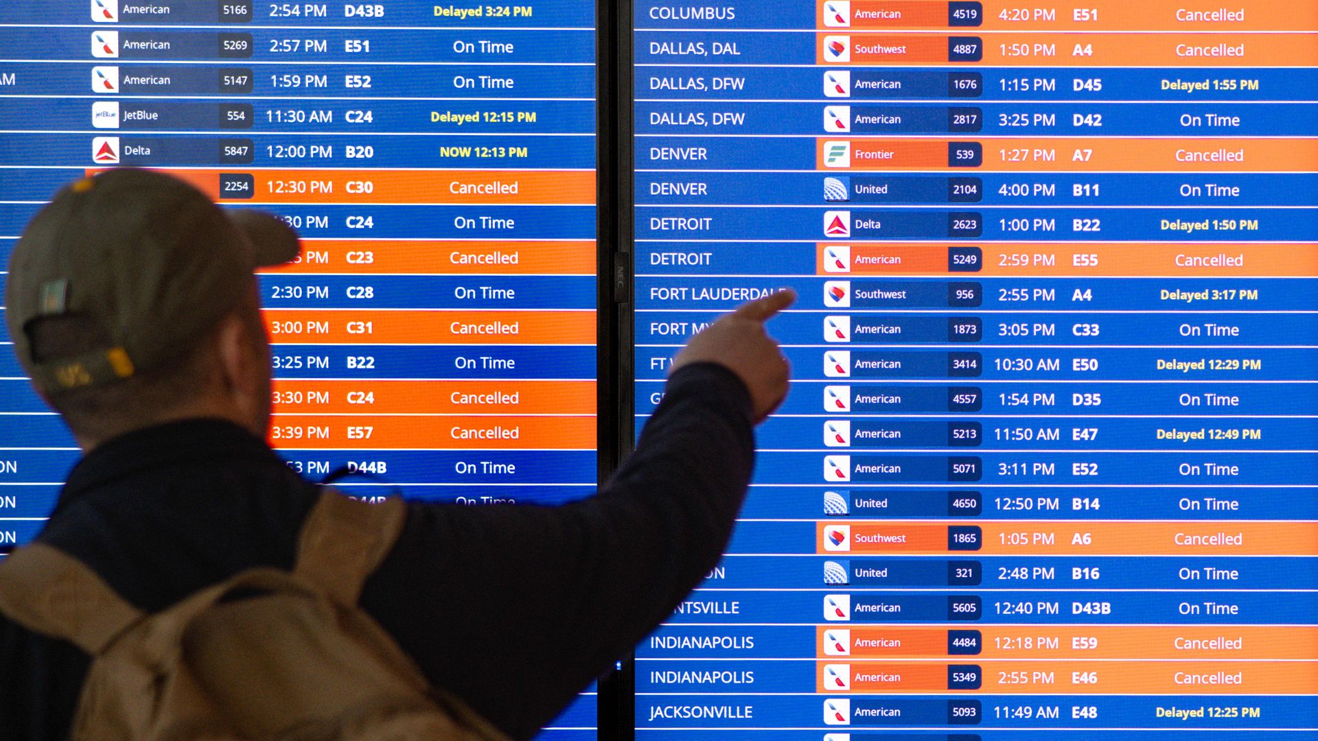 Traveler in front of flight status board.
