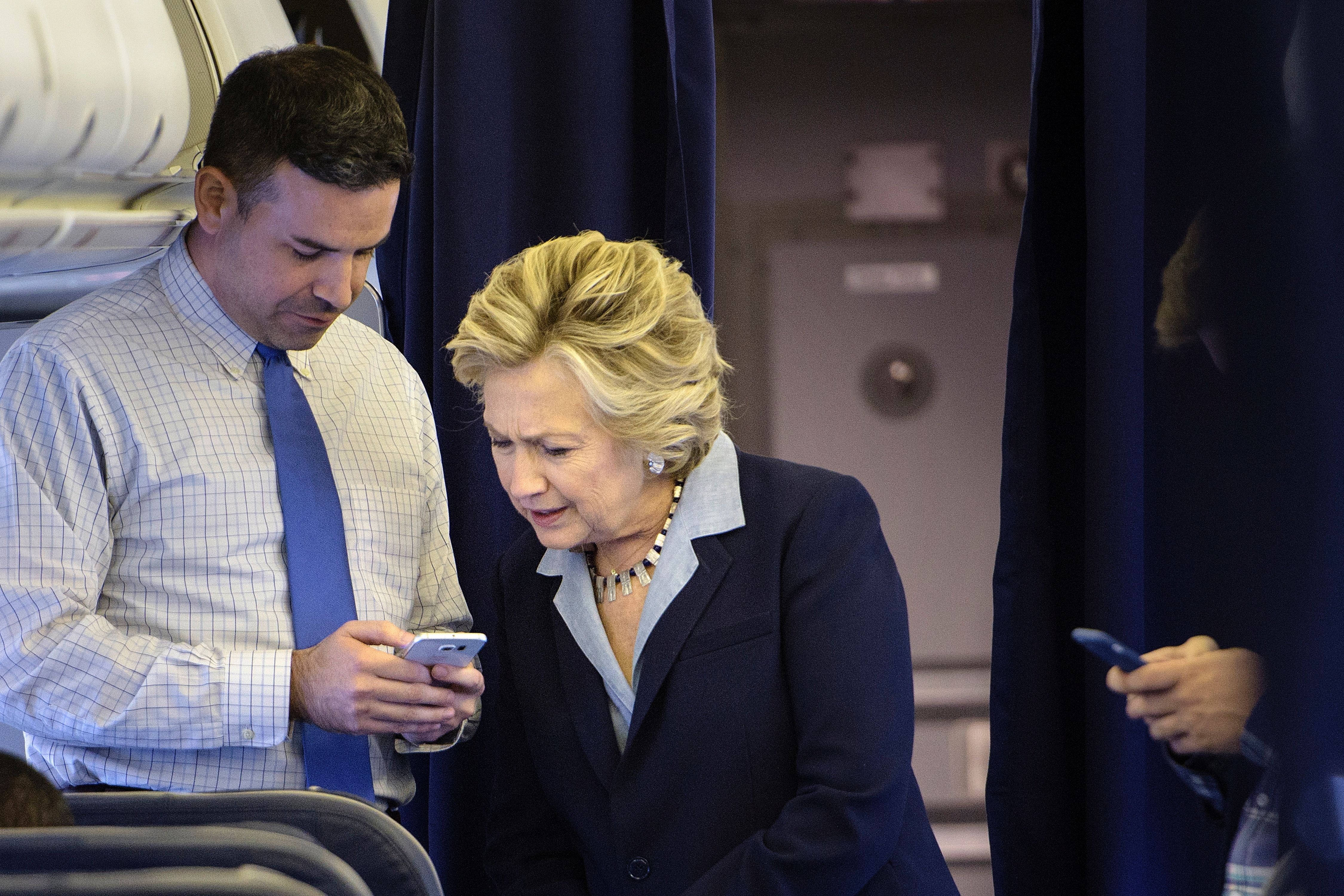 Democratic presidential nominee Hillary Clinton looks at a smart phone with national press secretary Brian Fallon on her plane at Westchester County Airport October 3