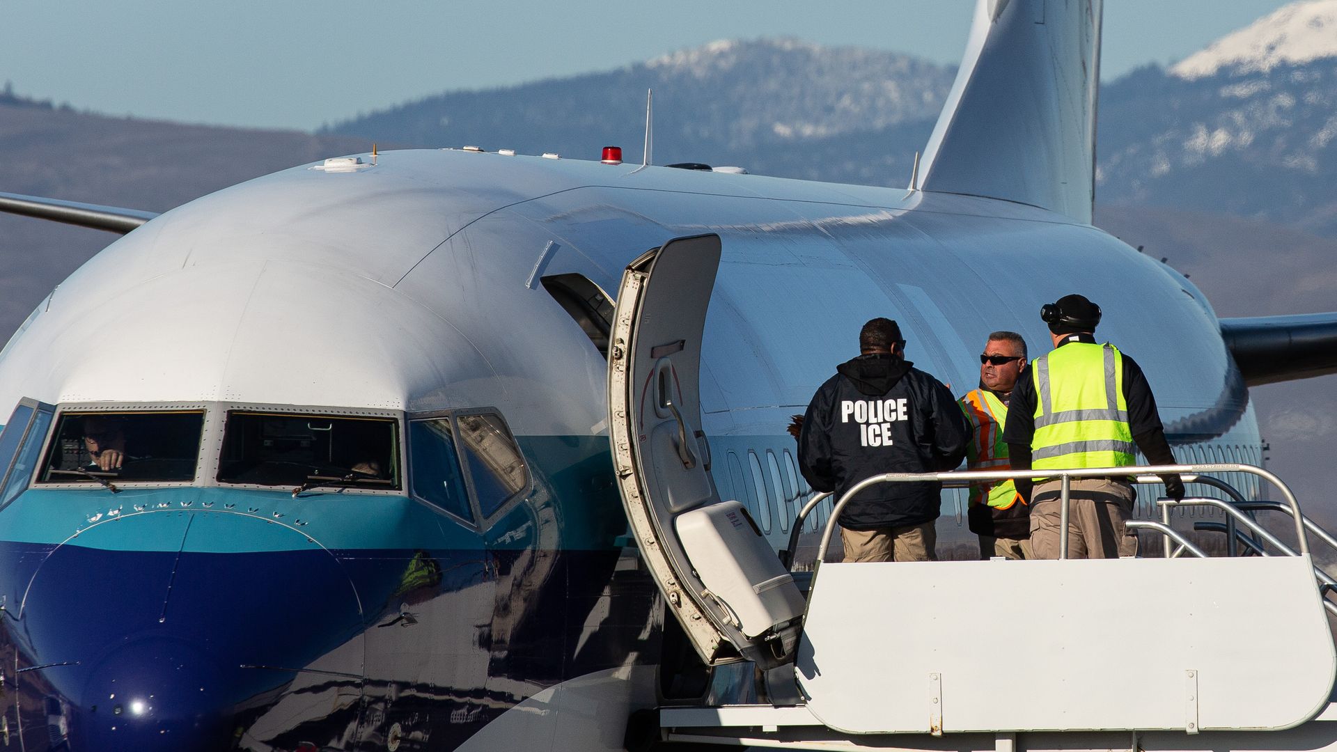 gents working for U.S. Immigration and Customs Enforcement (ICE) prepare to board detainees onto a Swift Air charter flight at McCormick Air Center 