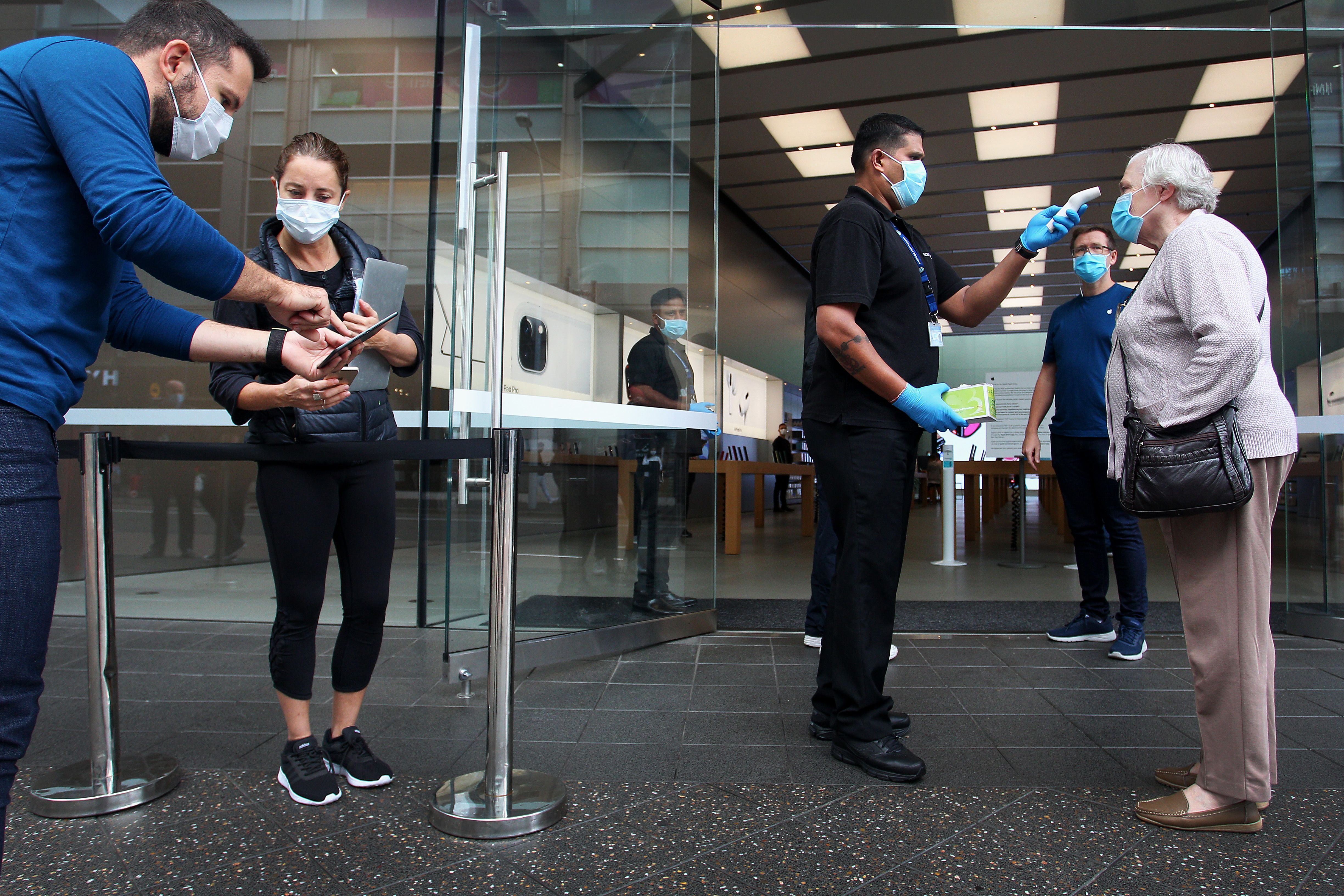 A customer has her temperature tested prior to entering the Apple Store at Bondi Junction on May 07