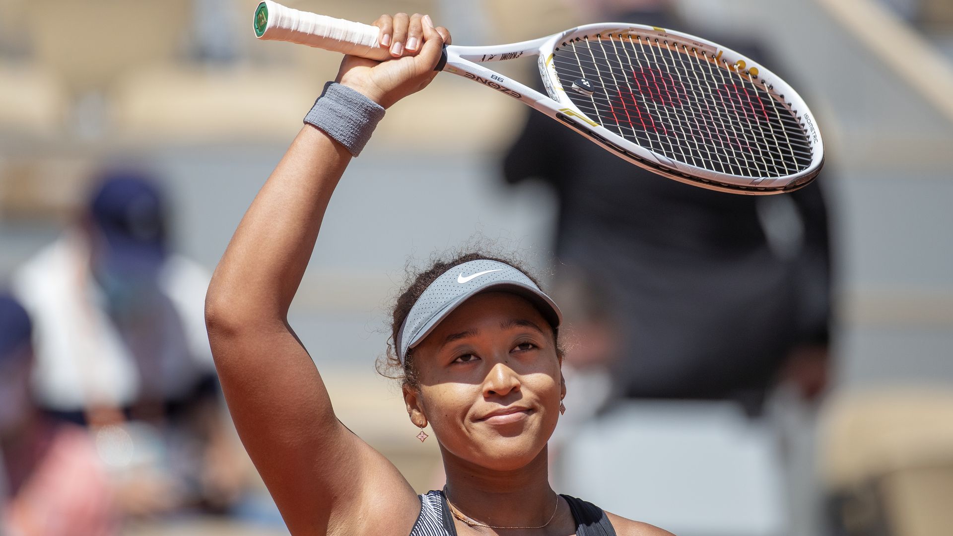 Naomi Osaka holding a tennis racket at a tennis match.