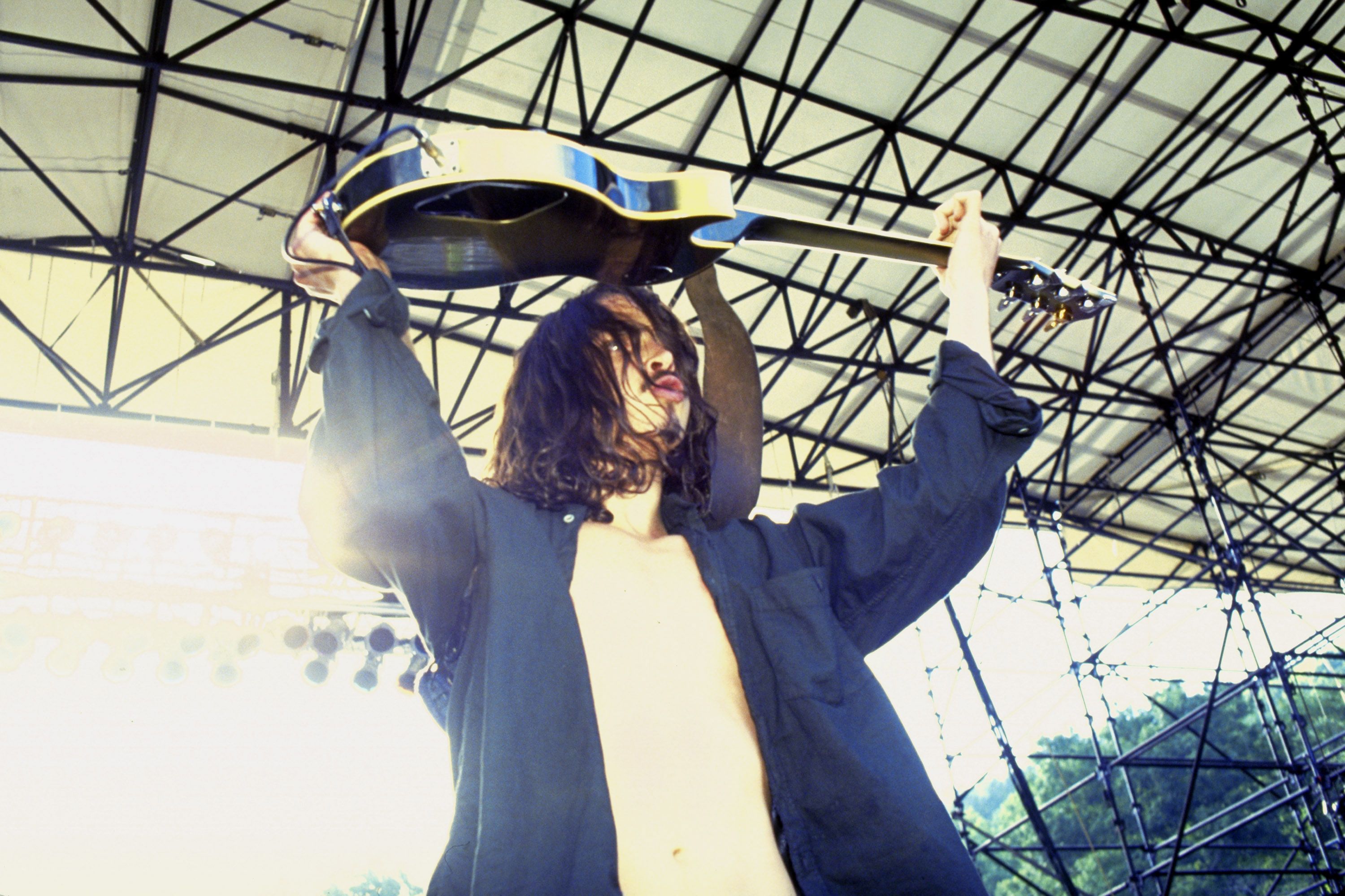 Chris Cornell of Soundgarden holds a guitar over his head on stage. 