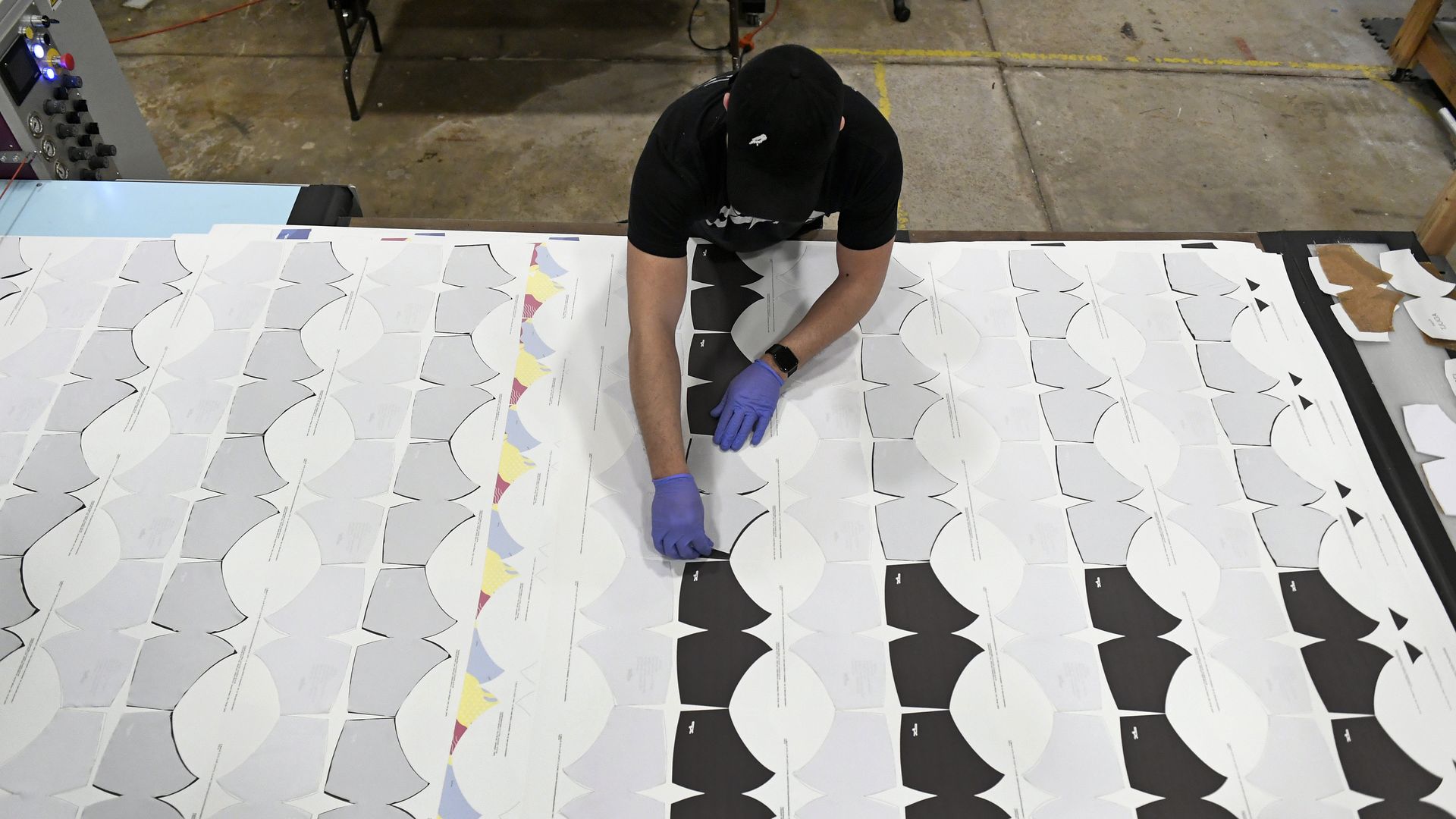 Andrew Martinez lines up fabric cutouts that will become masks at Xtreme Pro Apparel on March 23, 2020 in Broomfield, Colorado. 