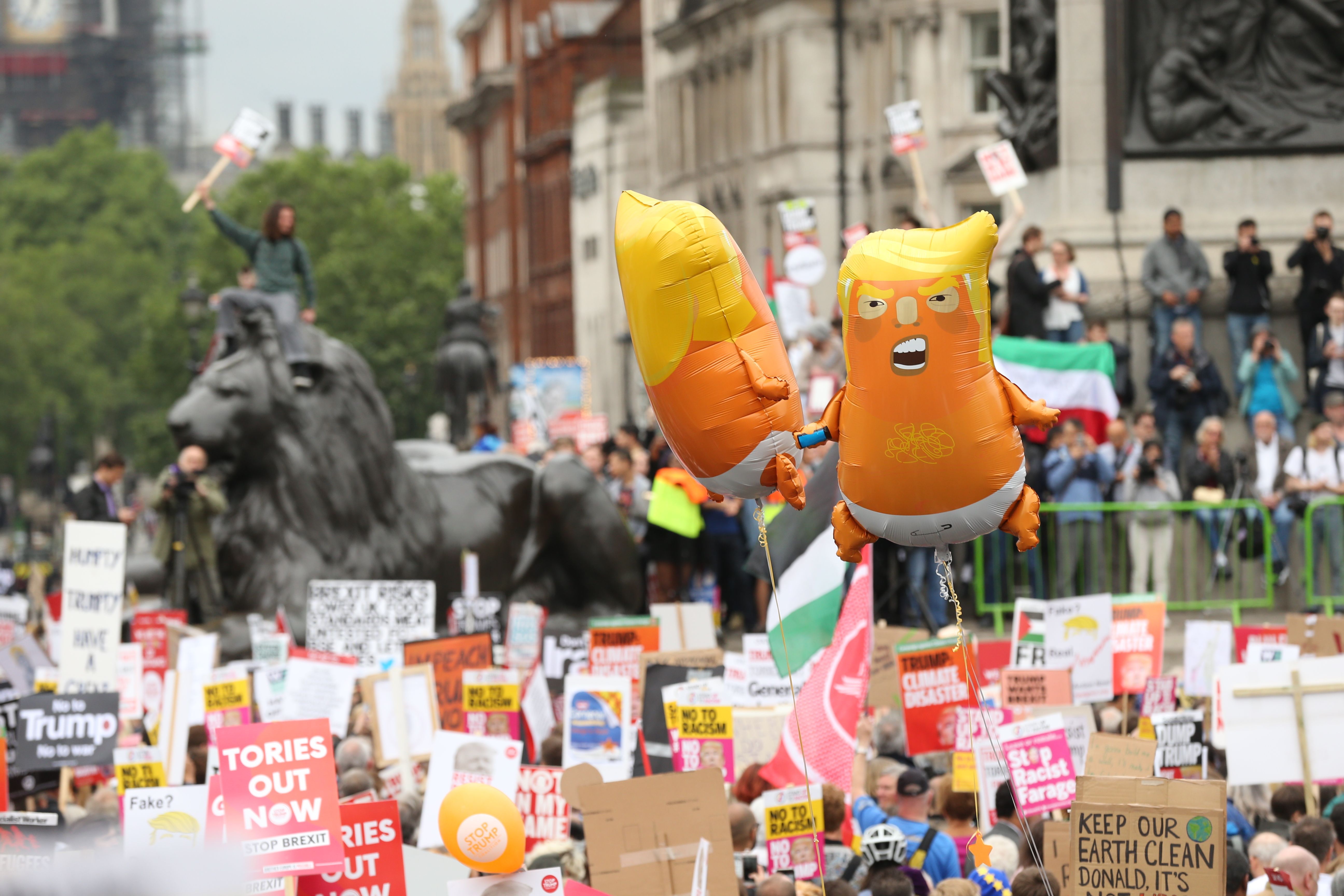 Anti-Trump protesters hold placards and balloons depicting US President Donald Trump as an orange baby as they gather in Trafalgar Square.