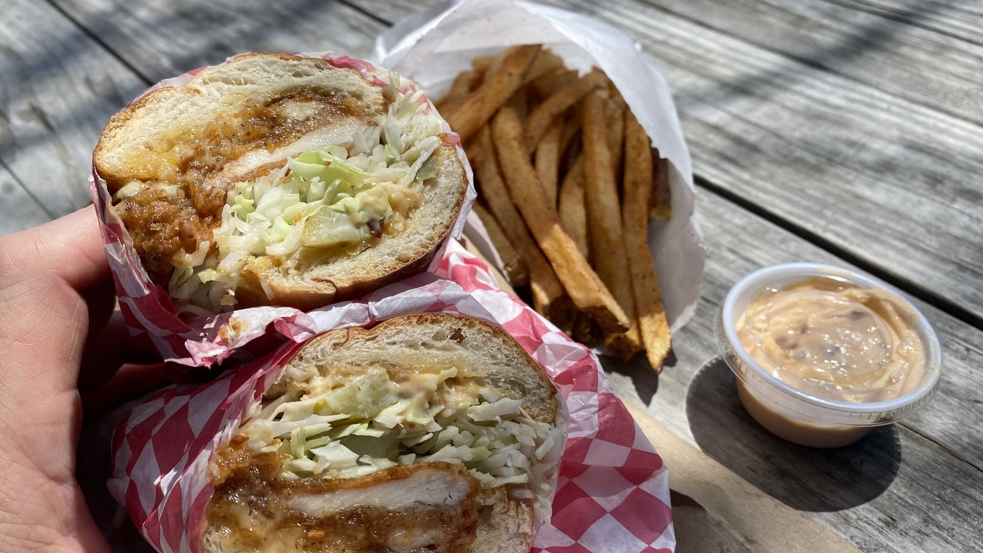Picture of a chicken sandwich with fries in the background.