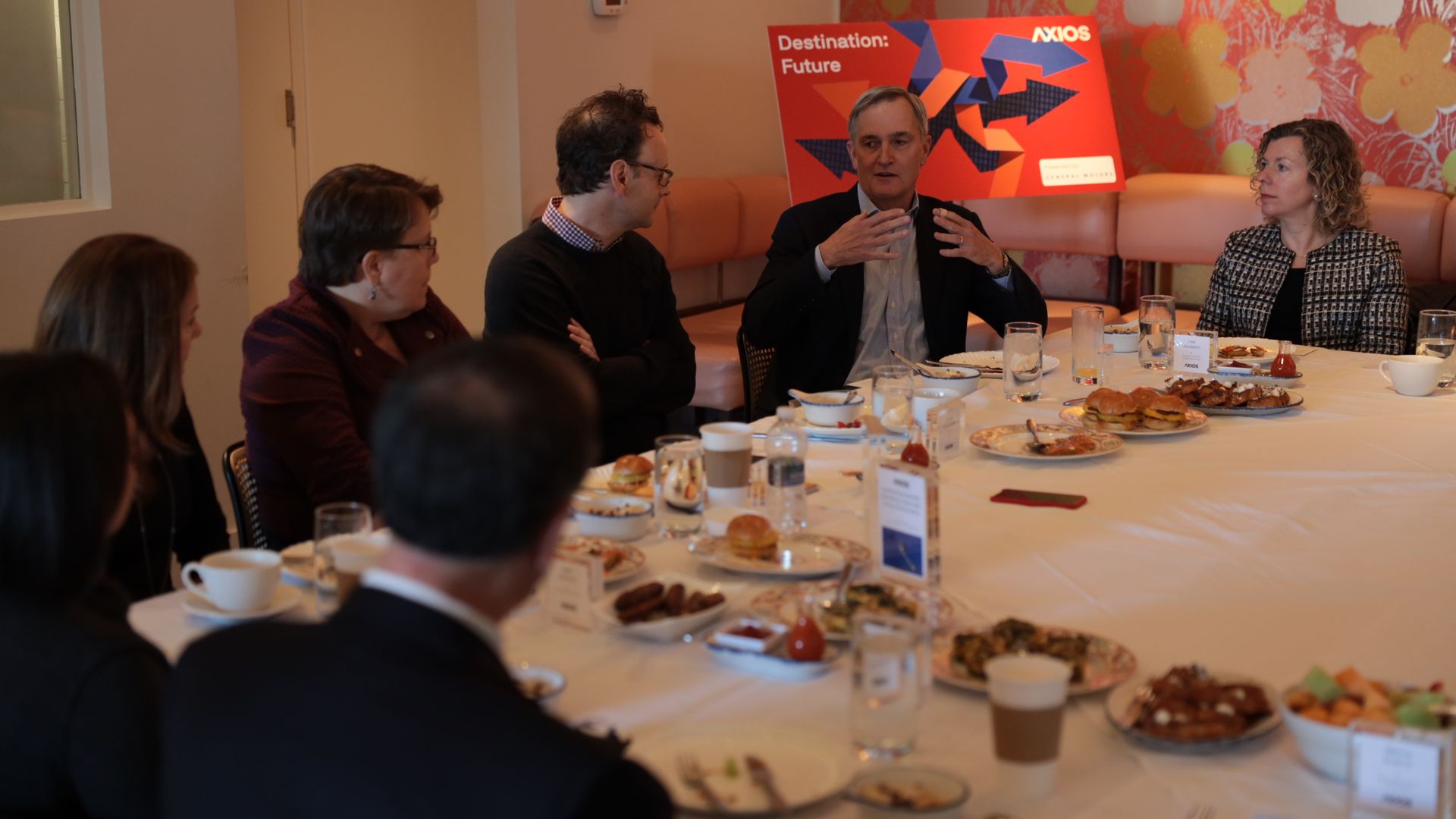 Local leaders sit at a table watching one participant speak.