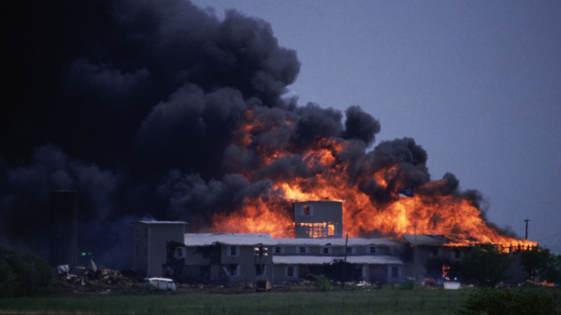 A photo of the compound on fire with a cloud of smoke to blowing to the left.