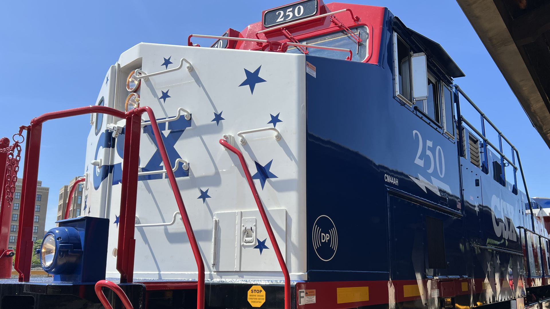 Side view of a blue locomotive with a white front panel covered in blue stars, red handrails, and a red cab roof; the number 250 is displayed on the front/top.