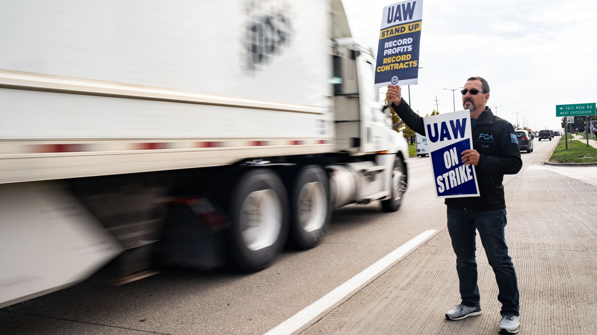 A person holding picket signs outside of a Stellantis plant in Sterling Heights, Michigan, in October 2023.